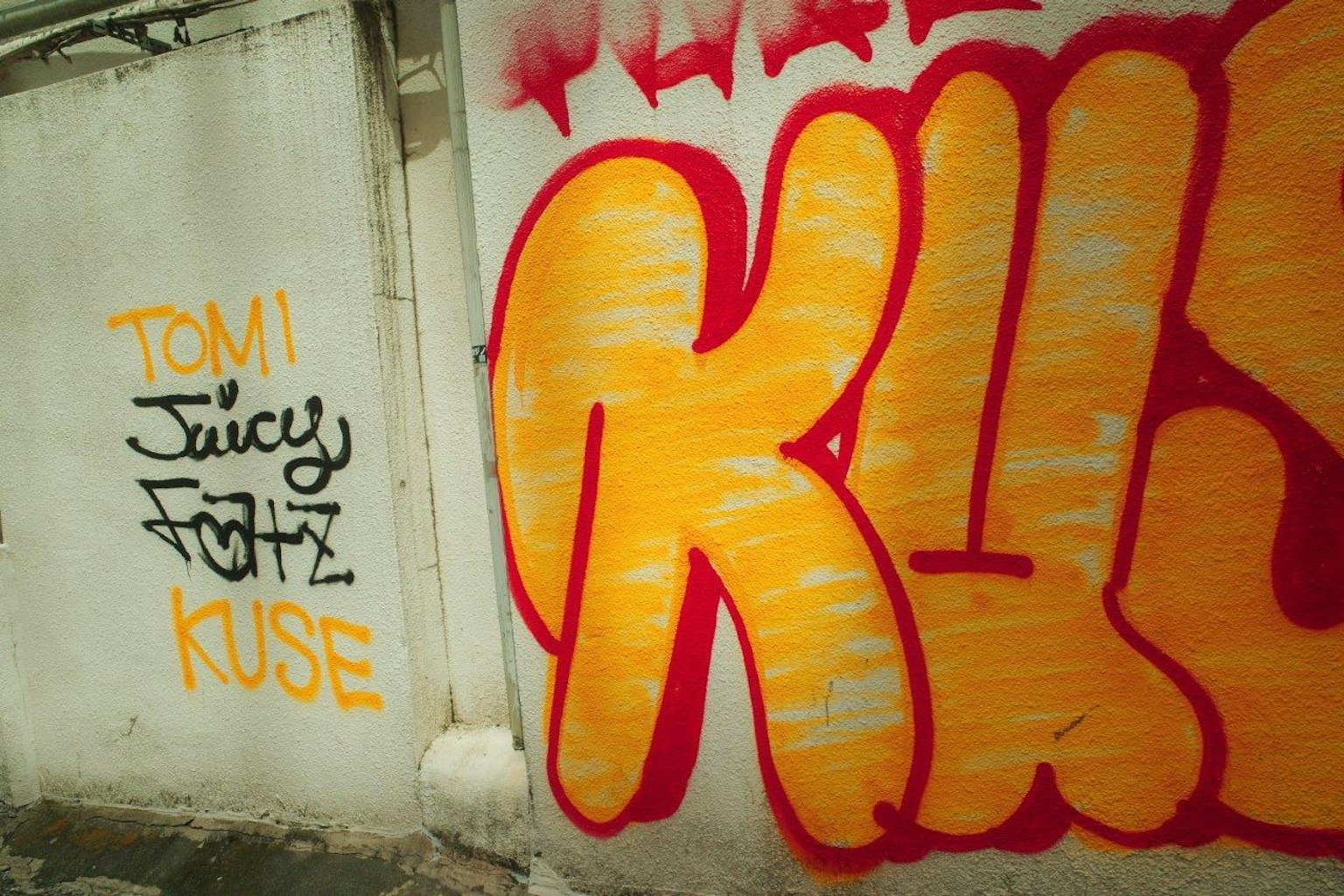 Vibrant graffiti art on a wall featuring the words KUSE and TOM JUICY