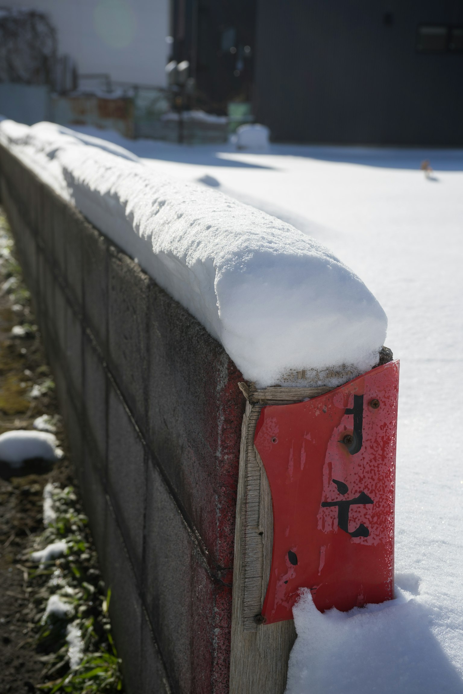 Snow-covered block wall with distinctive snow shape on top and red section