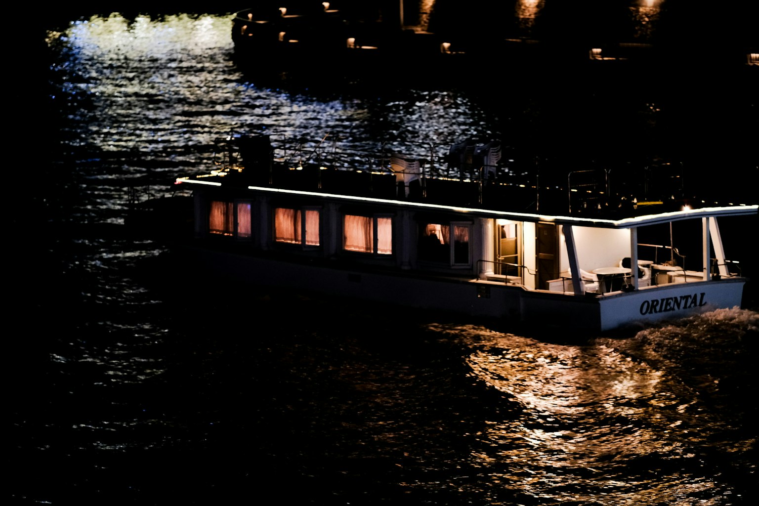 เรือที่มีแสงไฟลอยอยู่บนแม่น้ำในตอนกลางคืน