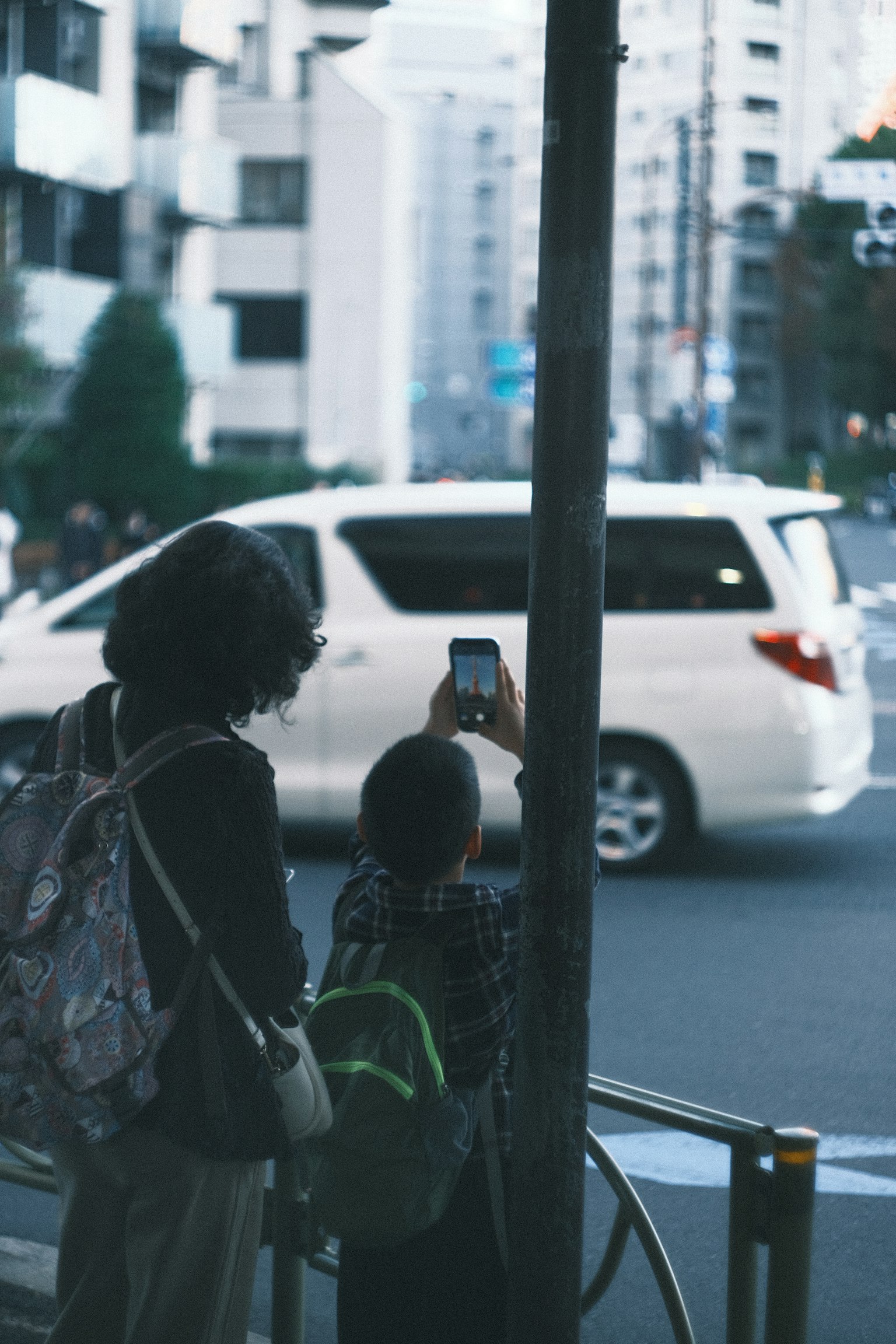 Một đứa trẻ cầm smartphone và một người lớn đứng trong bối cảnh đô thị