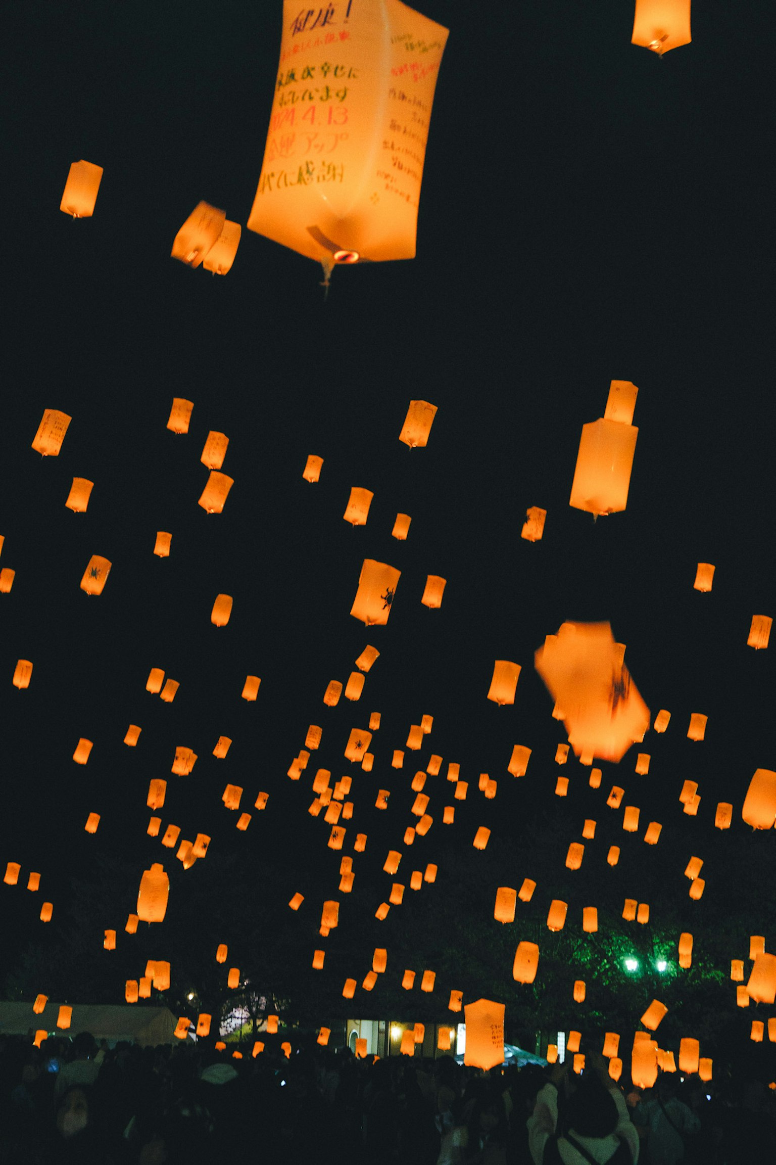 Numerous orange lanterns floating in the night sky