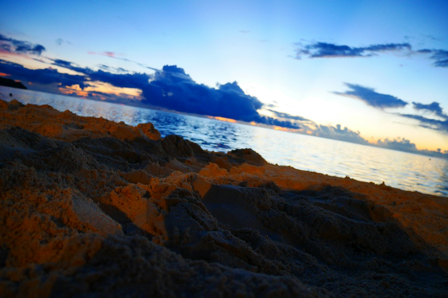 Playa y océano al atardecer con cielo azul y nubes