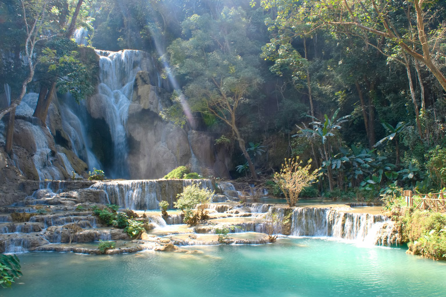 Malerscher Blick auf einen Wasserfall mit türkisfarbenem Pool umgeben von üppigem Grün