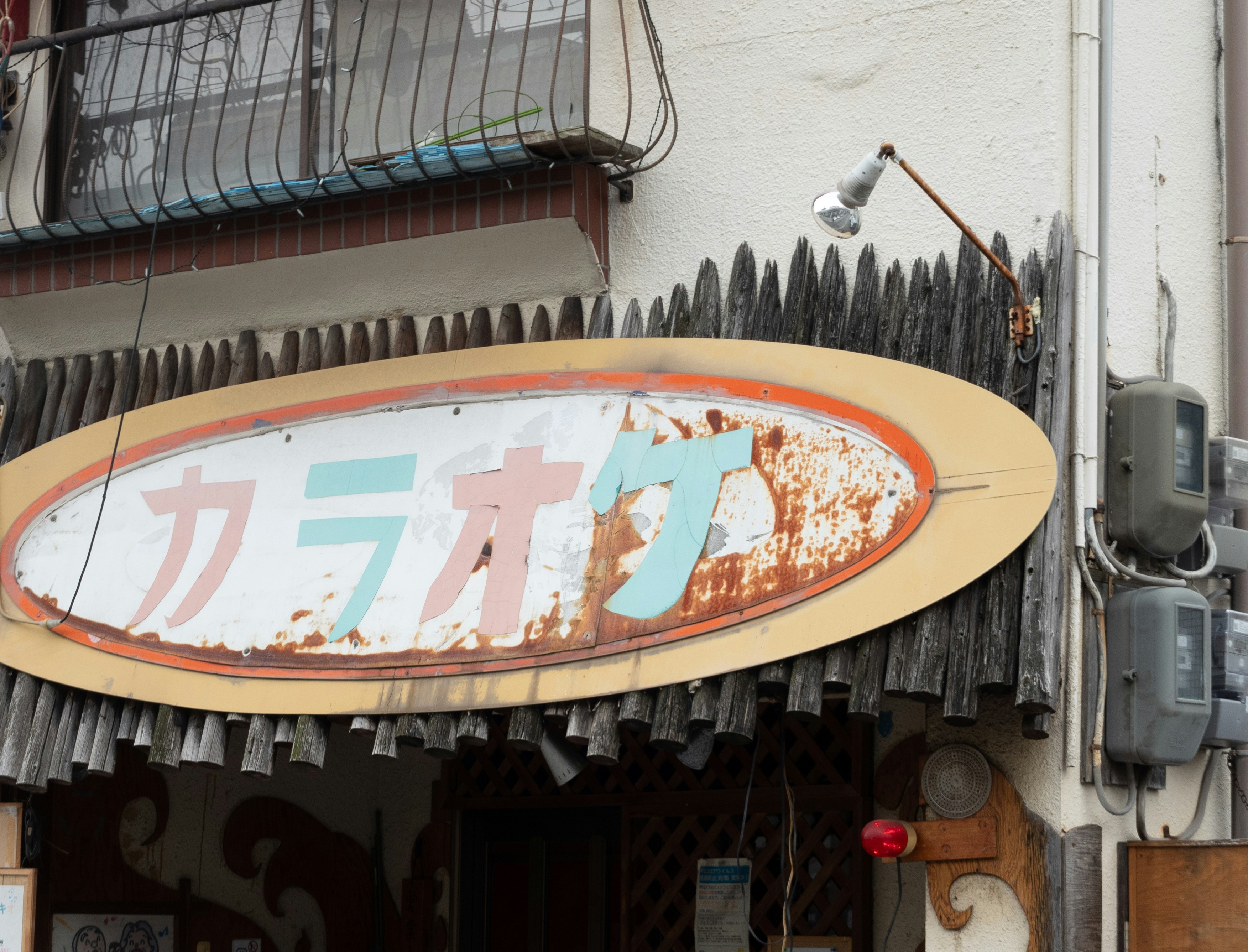 壁に掛かった「カラオケ」看板のある路地の店先