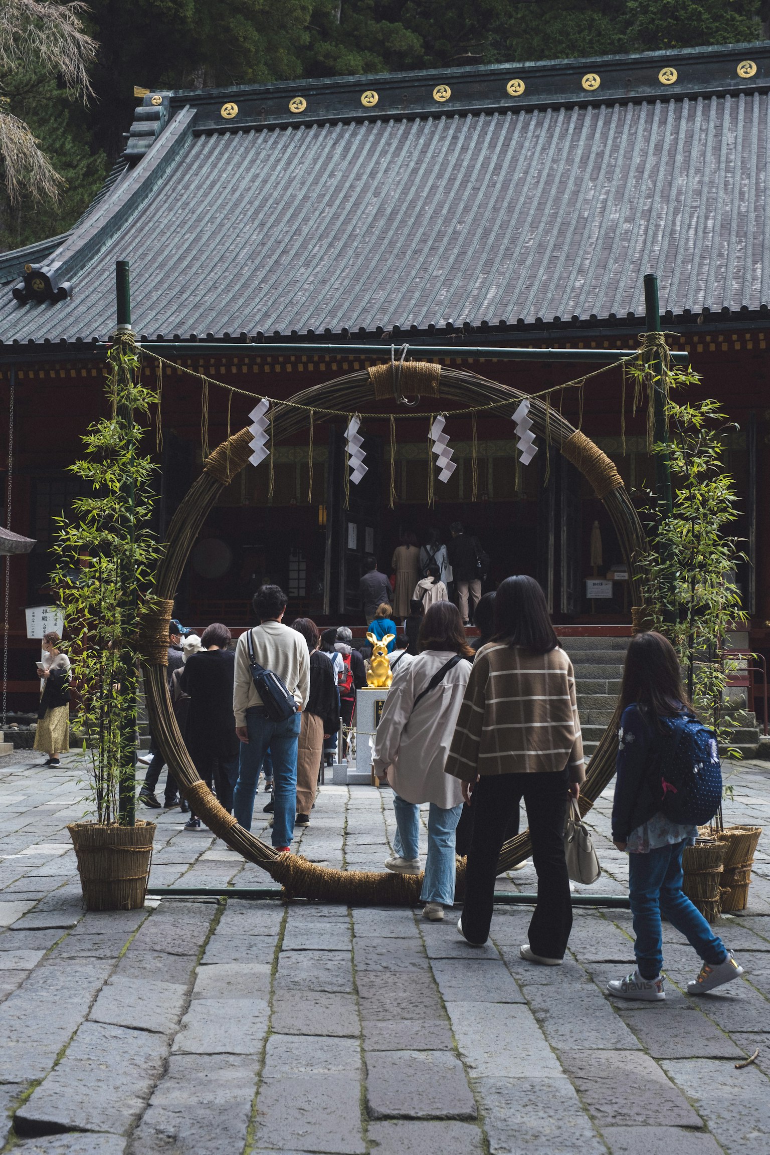 遊客穿過一個大型裝飾環走向傳統建築的神社