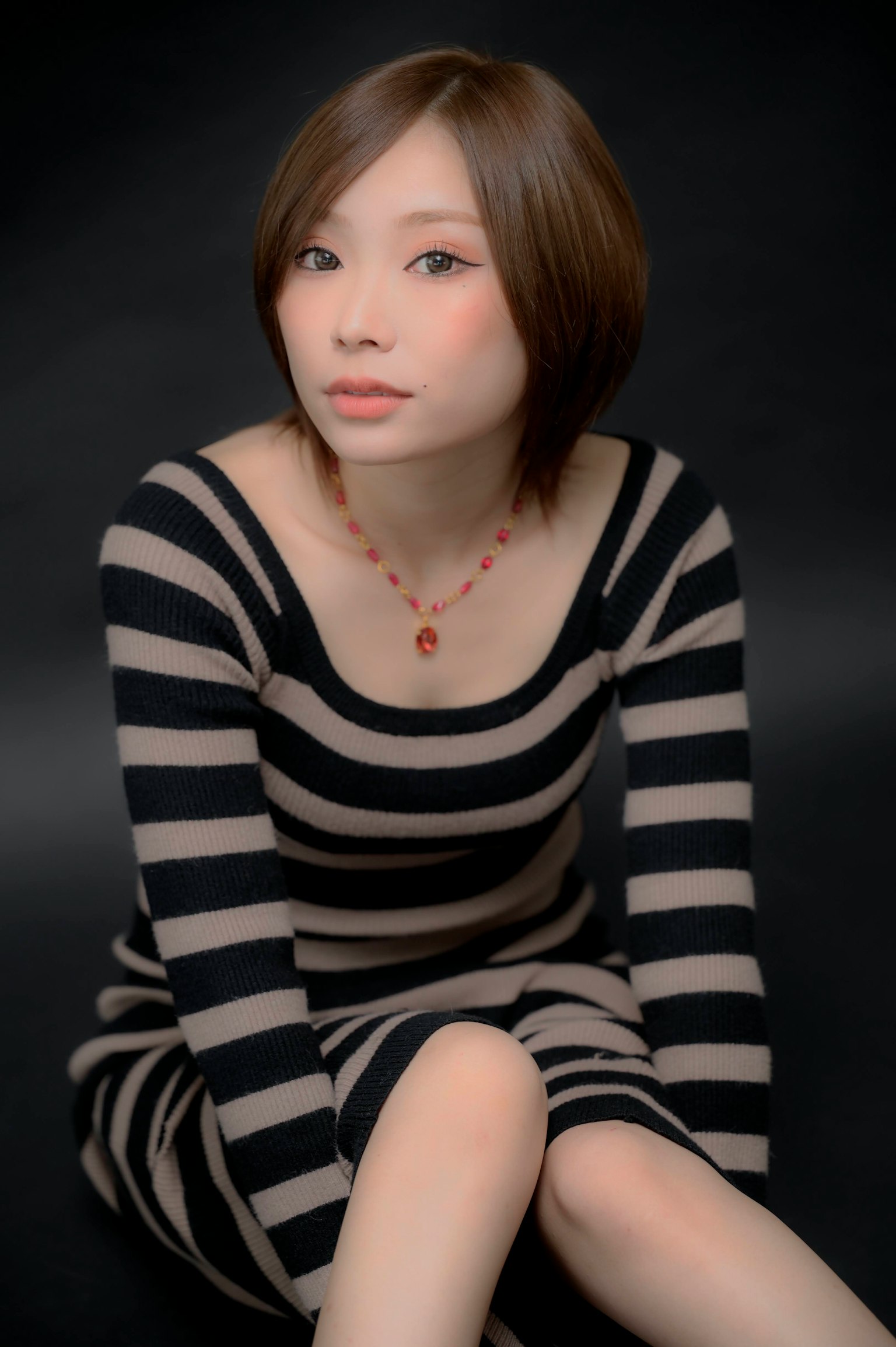 Femme assise dans une robe rayée sur fond noir
