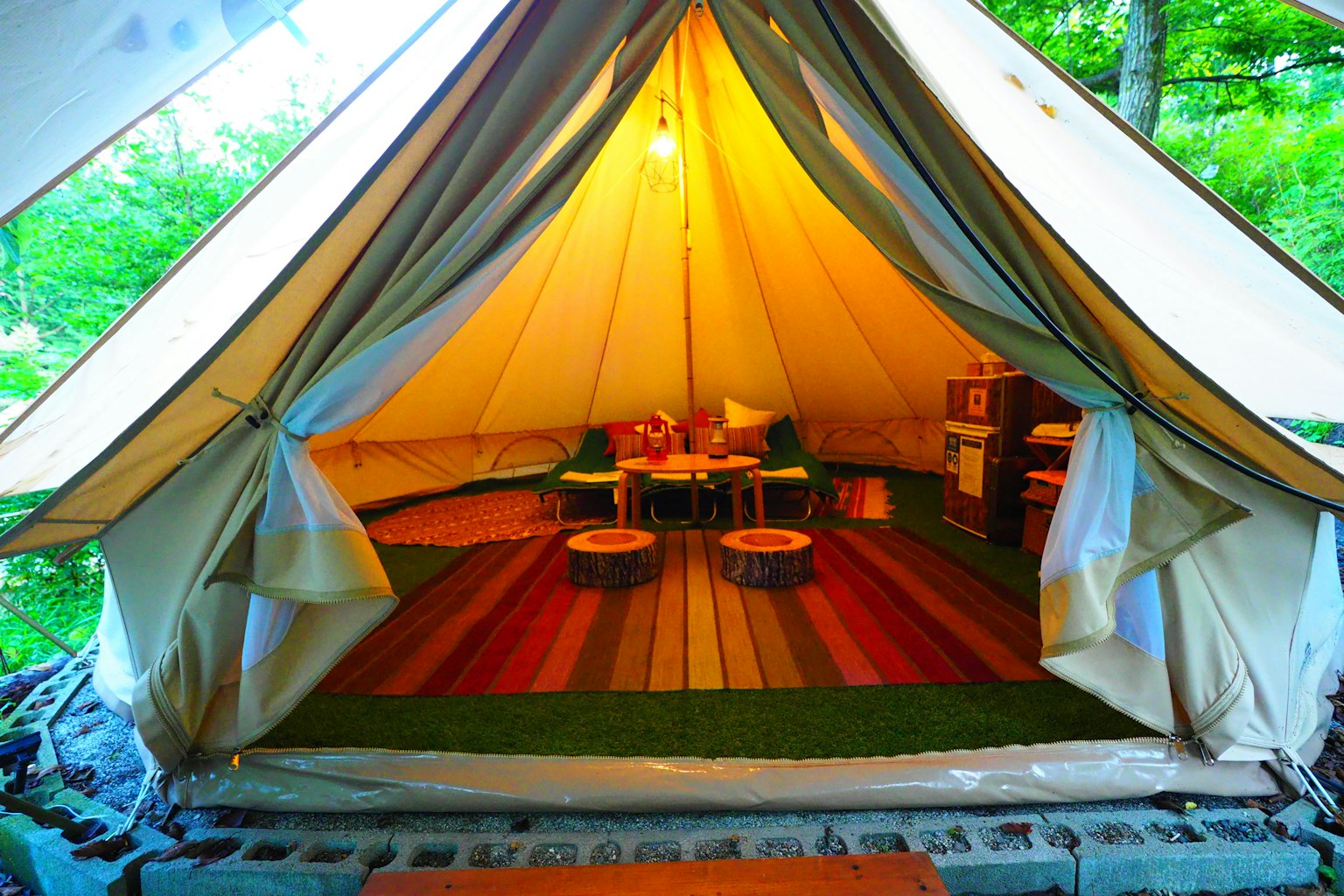 Interno di una tenda glamping accogliente con tappeto colorato e illuminazione calda