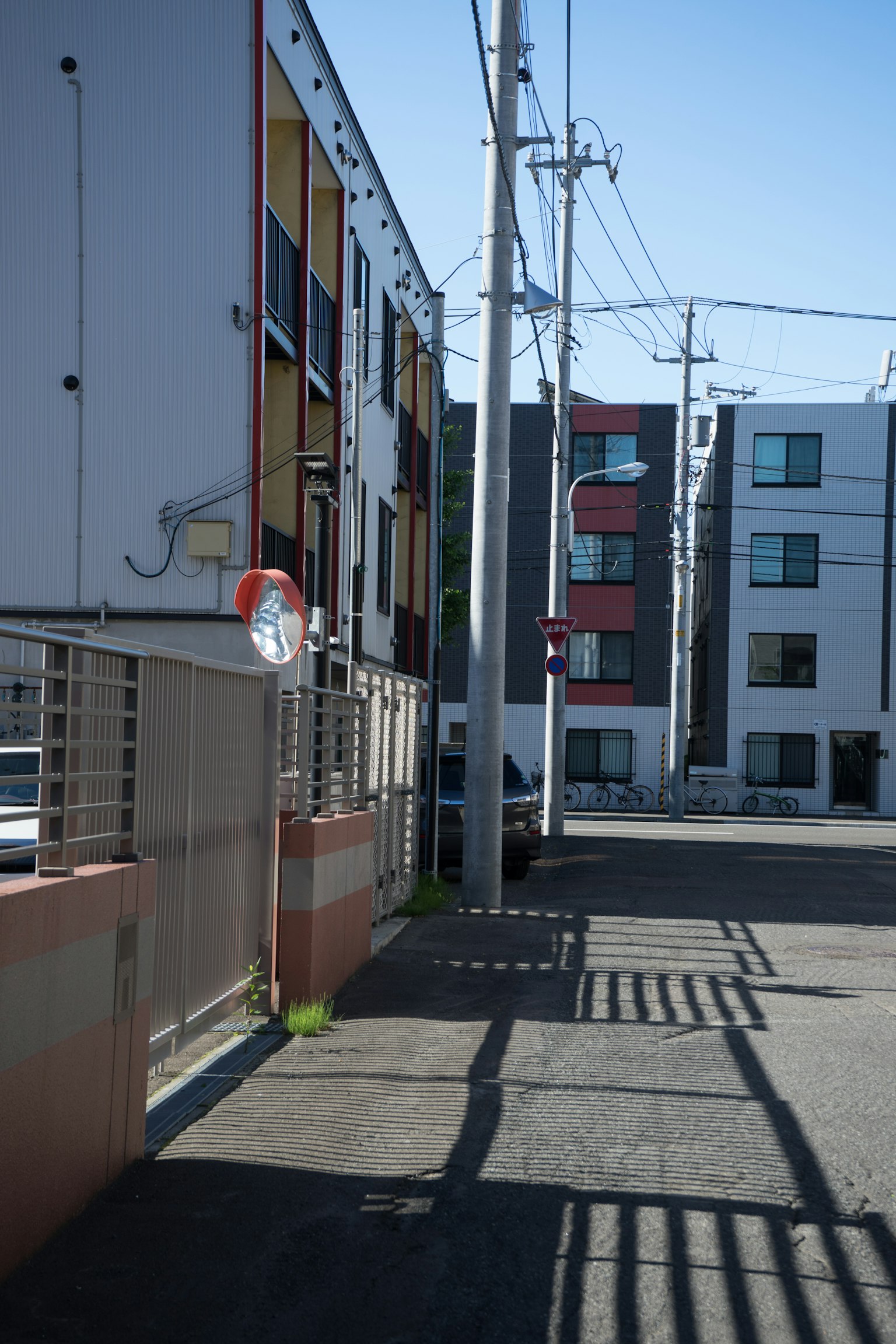 Vue de rue d'un quartier résidentiel sous un ciel bleu clair avec des bâtiments colorés et des poteaux utilitaires
