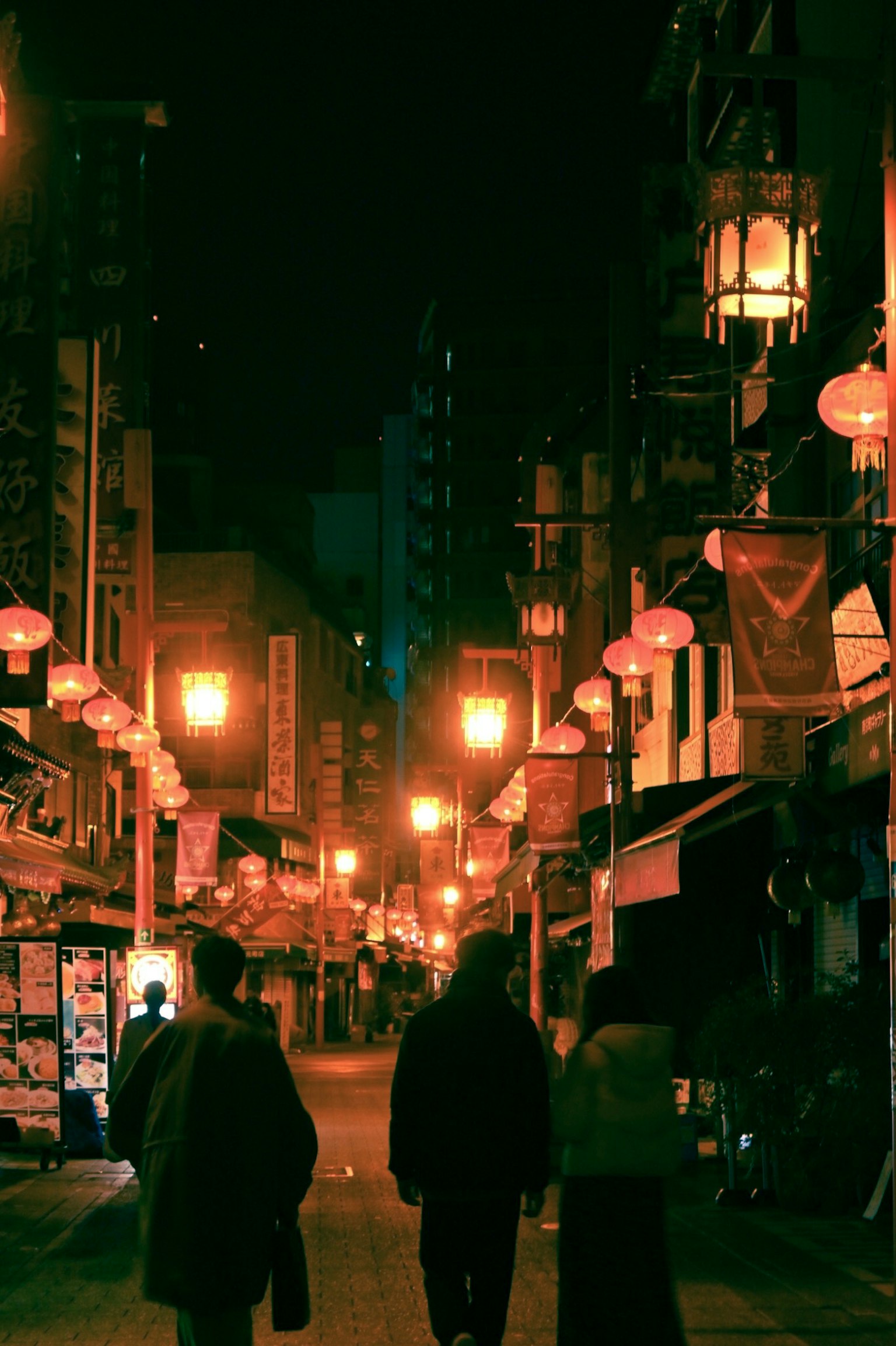 人們在夜晚走在有燈籠的街道上