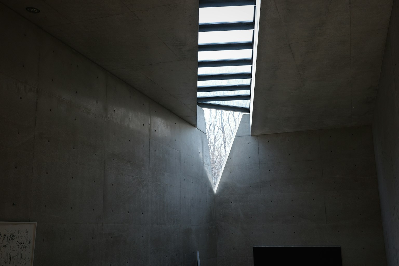 Interior space with concrete walls and a triangular skylight allowing natural light