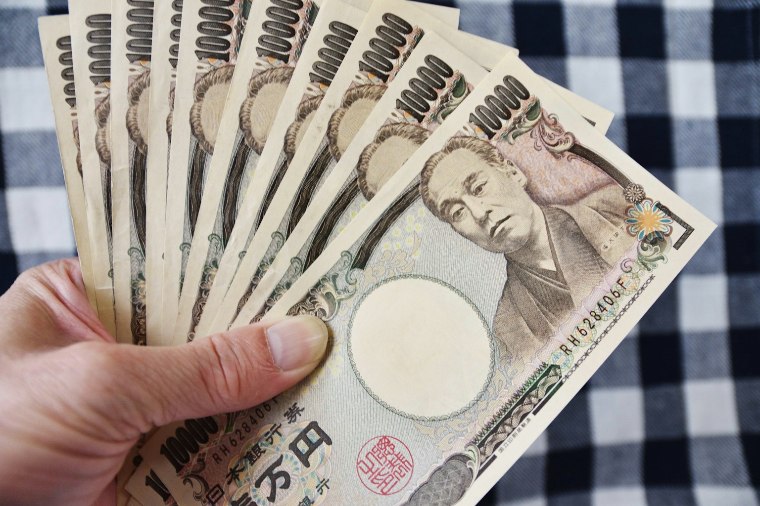 มือถือธนบัตร 10000 เยนหลายใบเรียงอย่างเป็นระเบียบ