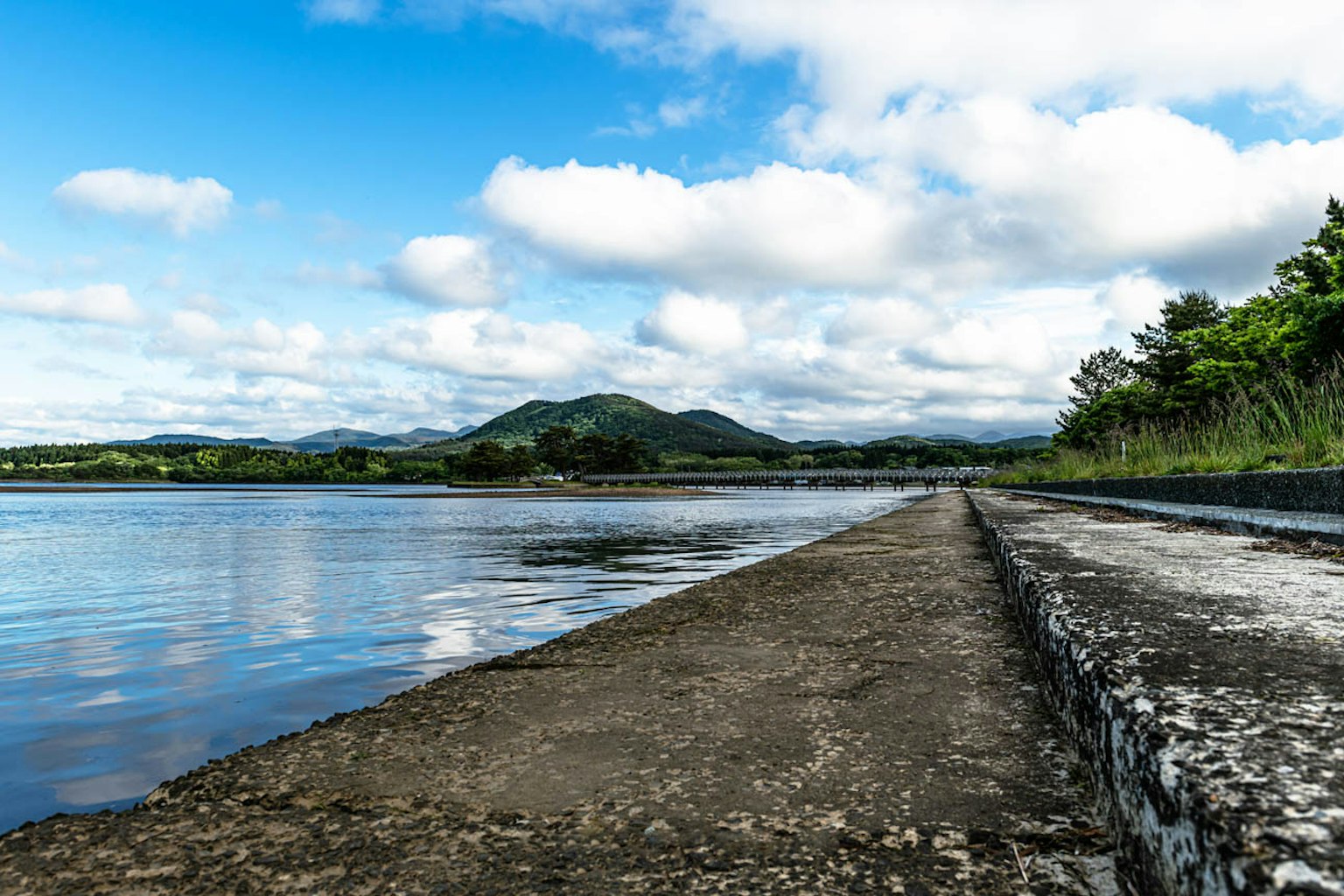 Vista escénica del río con cielo azul y nubes que muestra un dique de piedra y árboles verdes