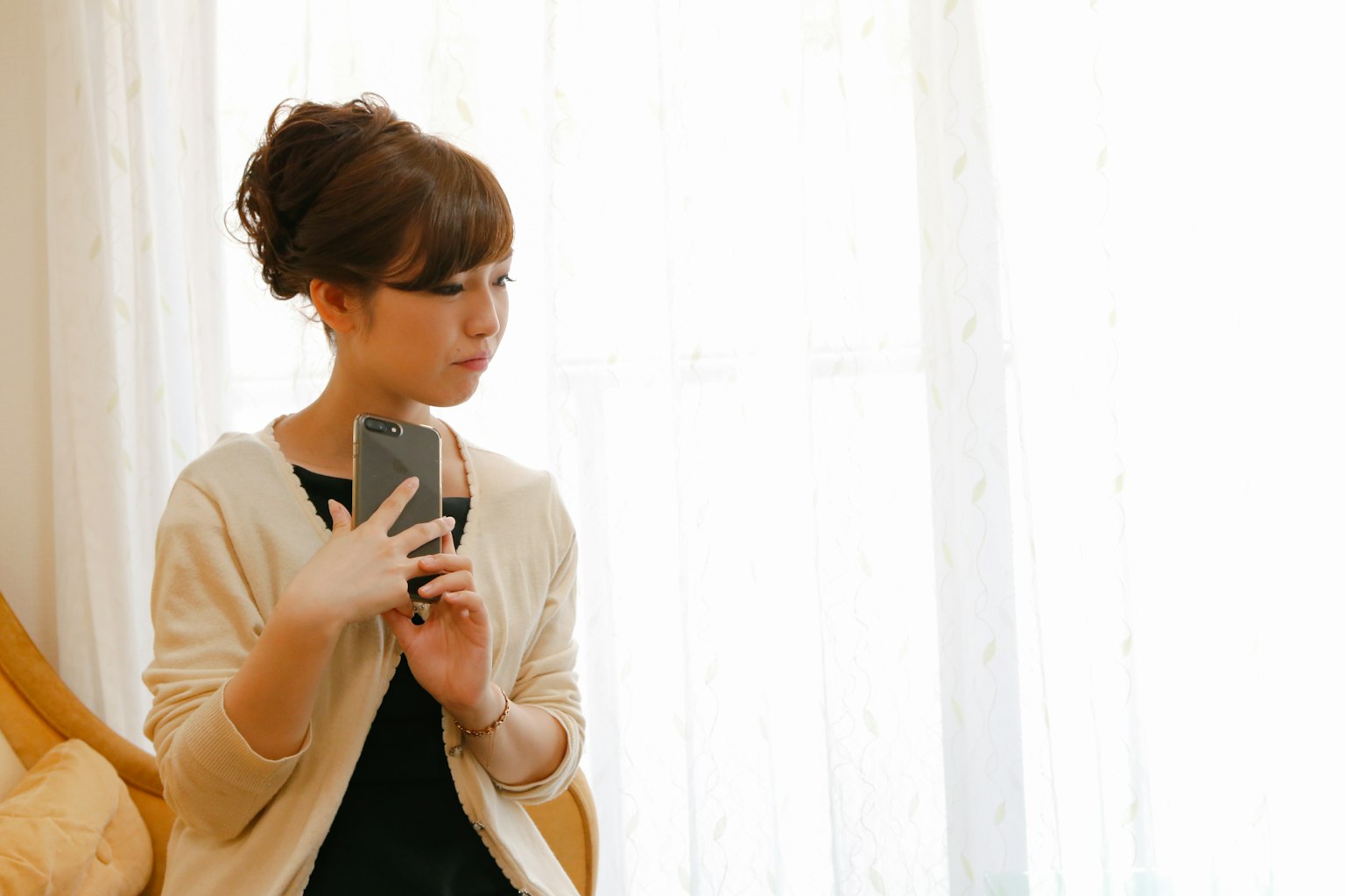 Một người phụ nữ cầm điện thoại thông minh với ánh sáng mềm mại từ cửa sổ