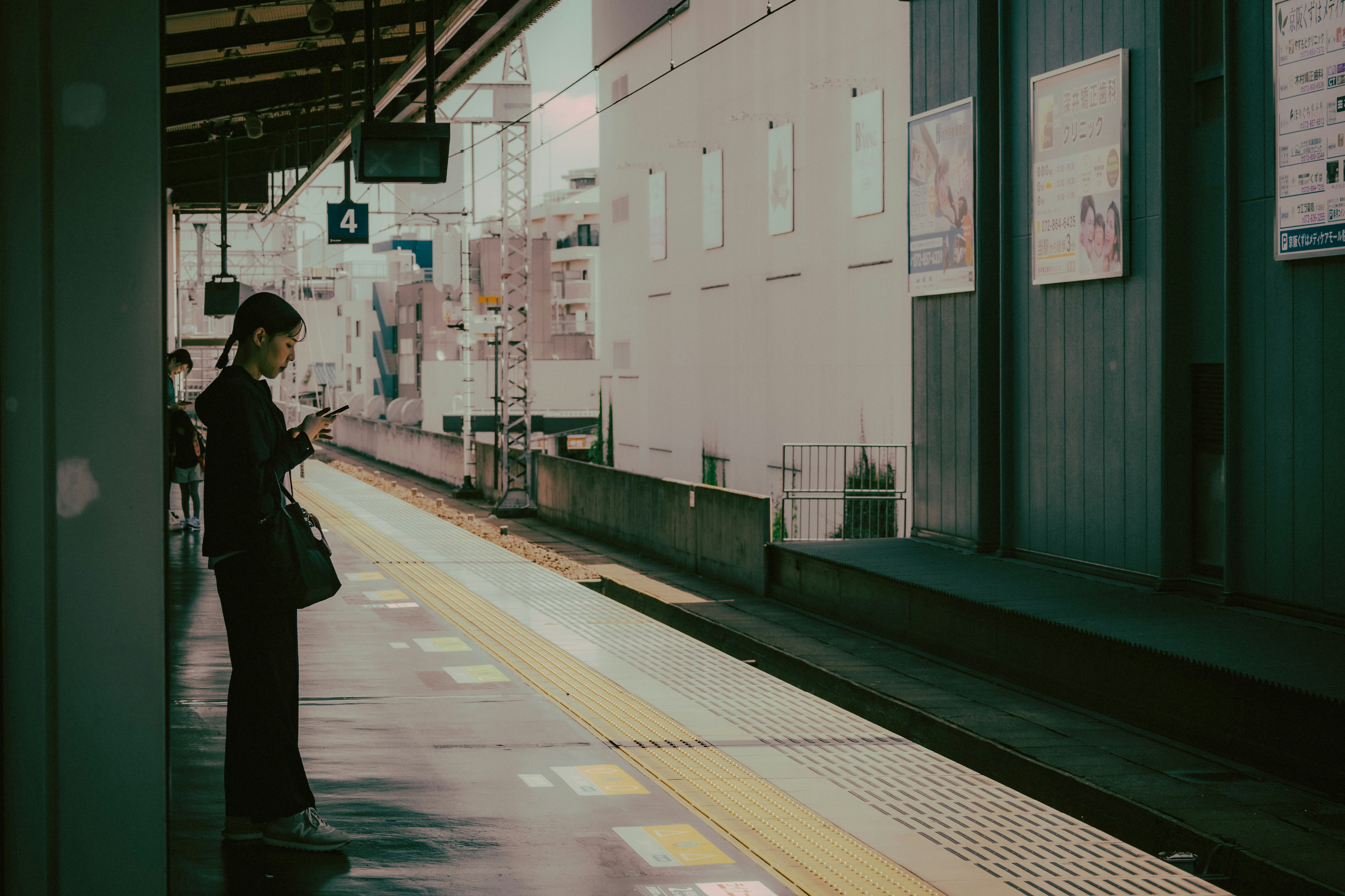 ホームの壁に掲示されたポスターと人影のある駅通路