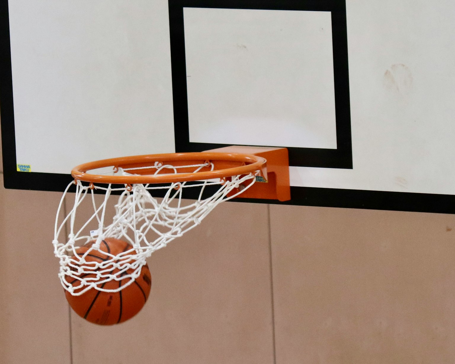 Canestro da basket con rete e palla in un ambiente di palestra