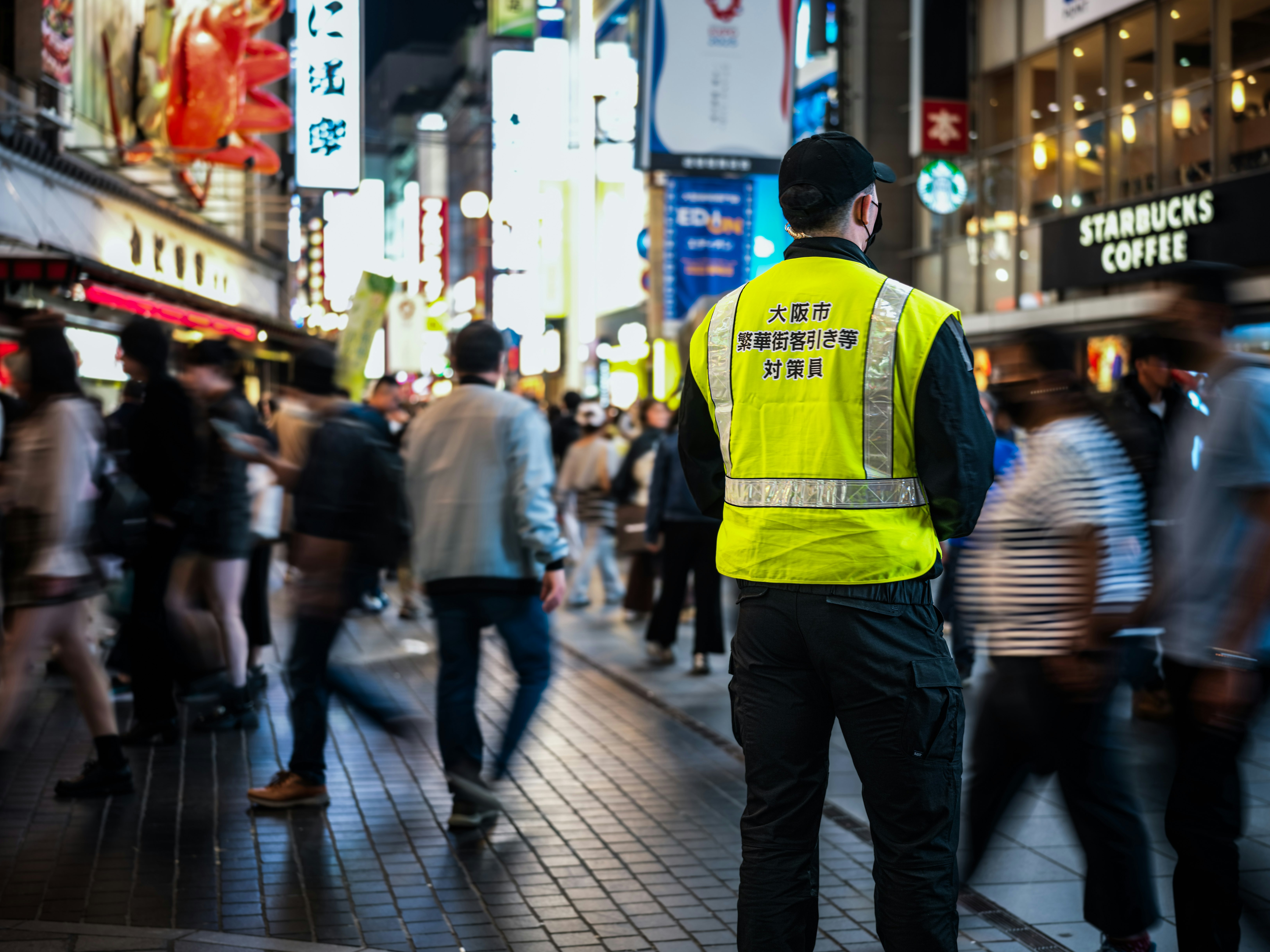 群衆の中で光る案内人の存在する大阪の夜の通り