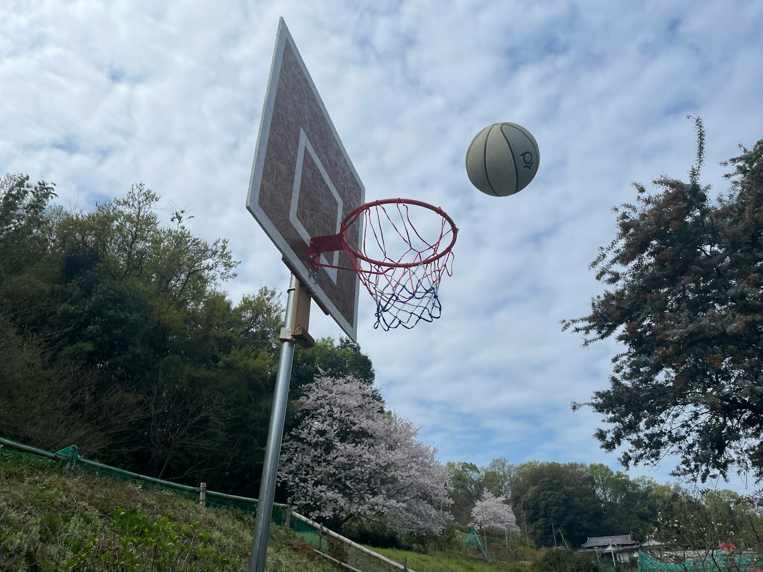 一个篮球接近篮筐，背景是阴云密布的天空