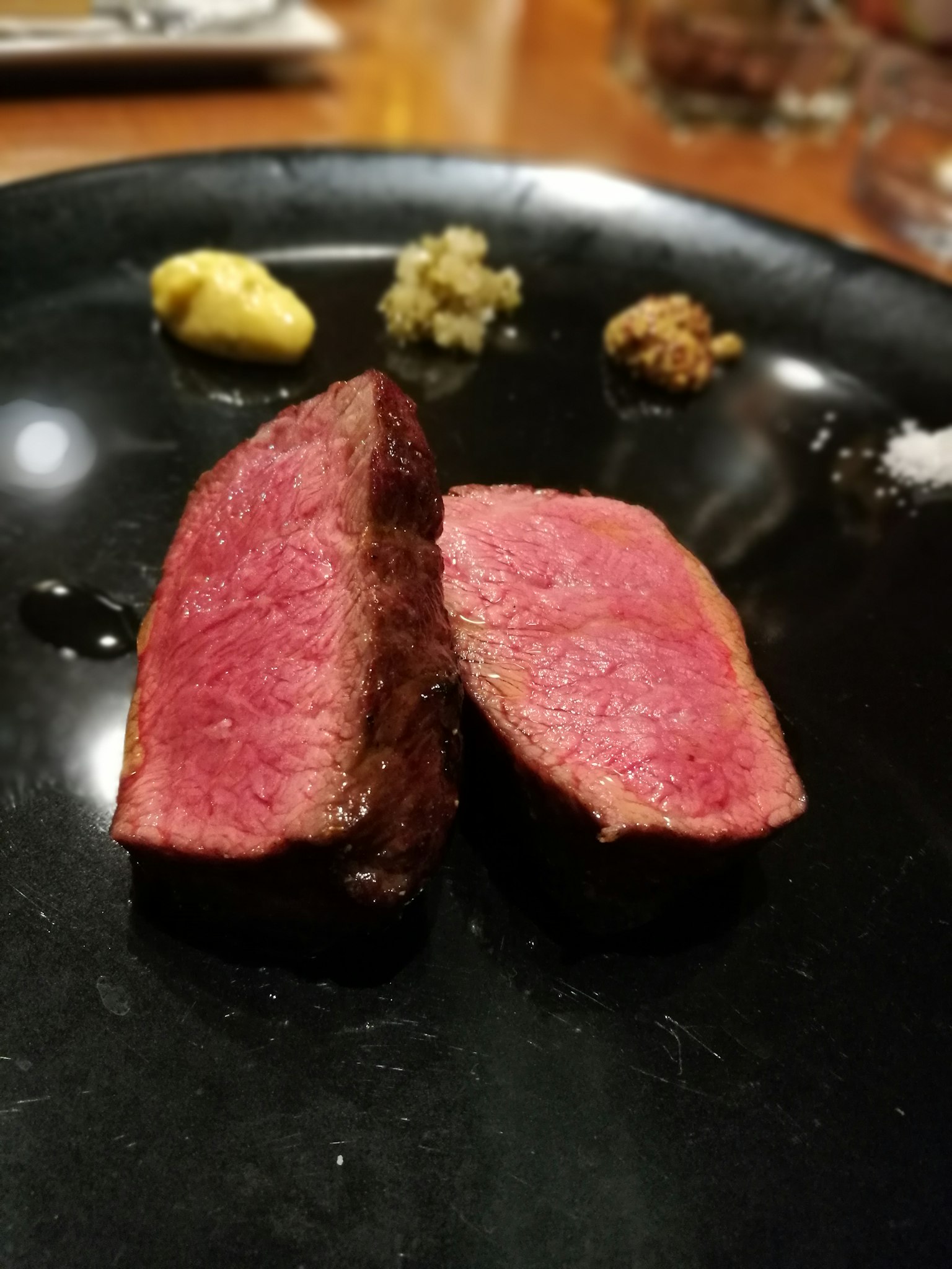 Tranches de steak juteuses sur une assiette noire avec des condiments d'accompagnement