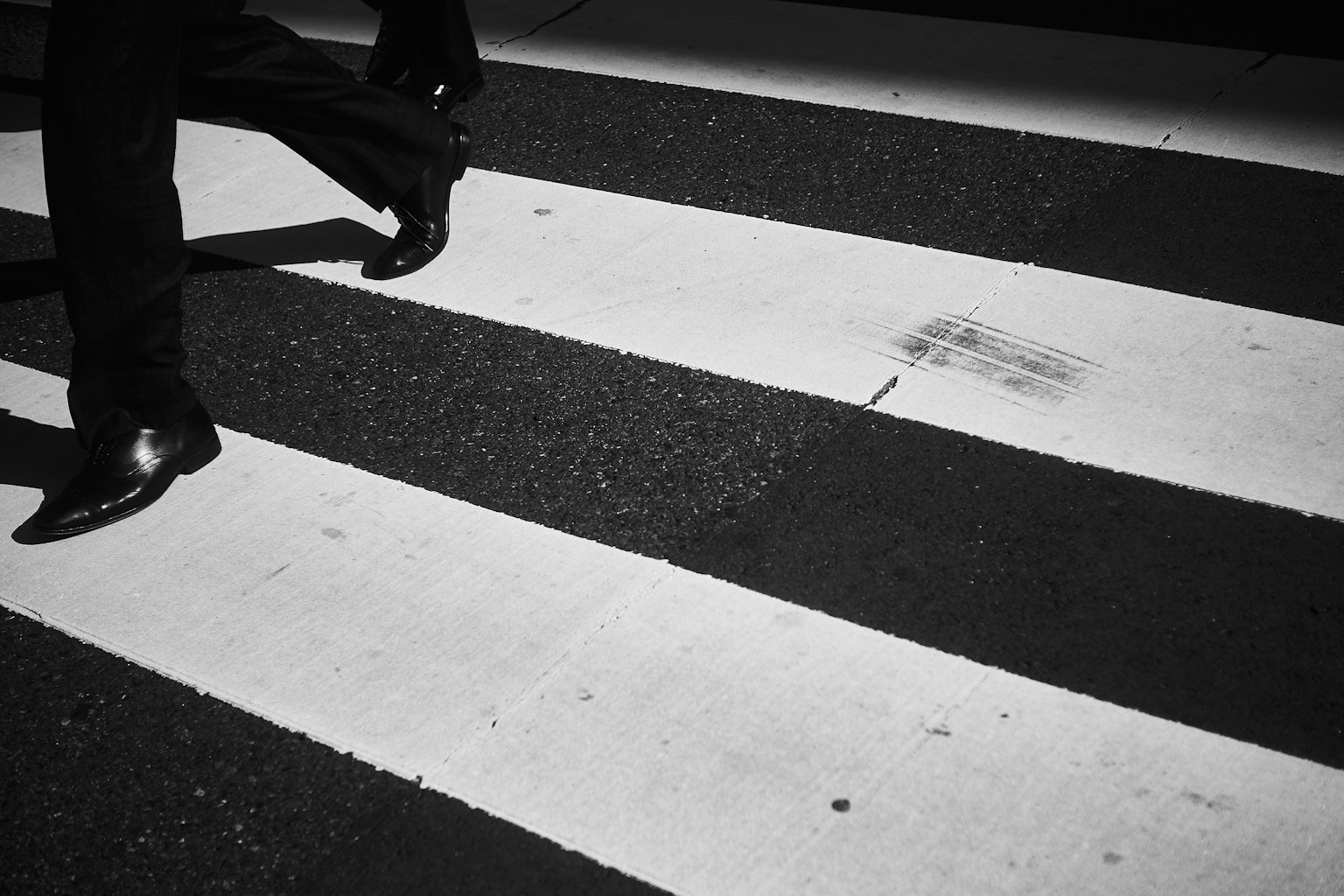 Un uomo d'affari che cammina su un attraversamento pedonale bianco e nero