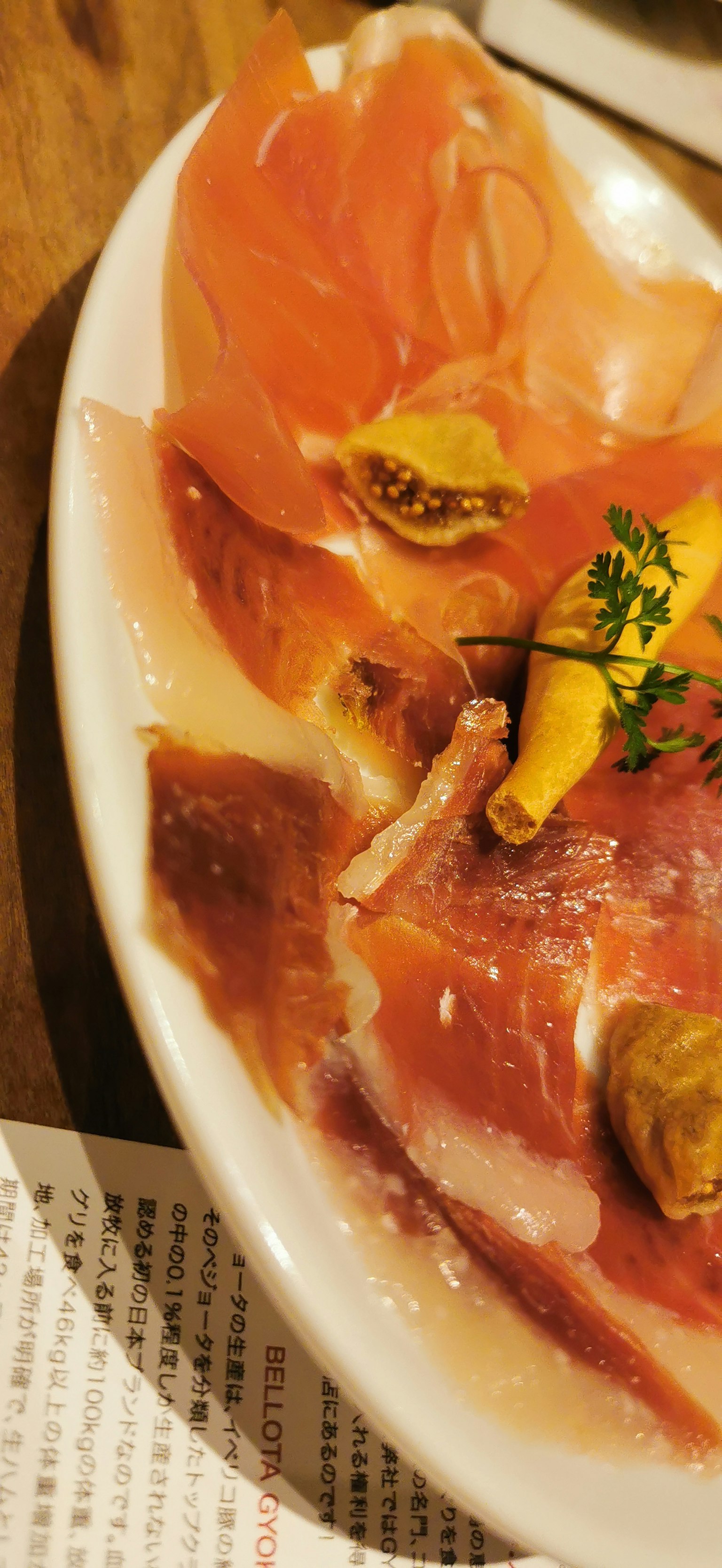 Piring prosciutto yang disusun dengan indah dengan hiasan bunga oranye