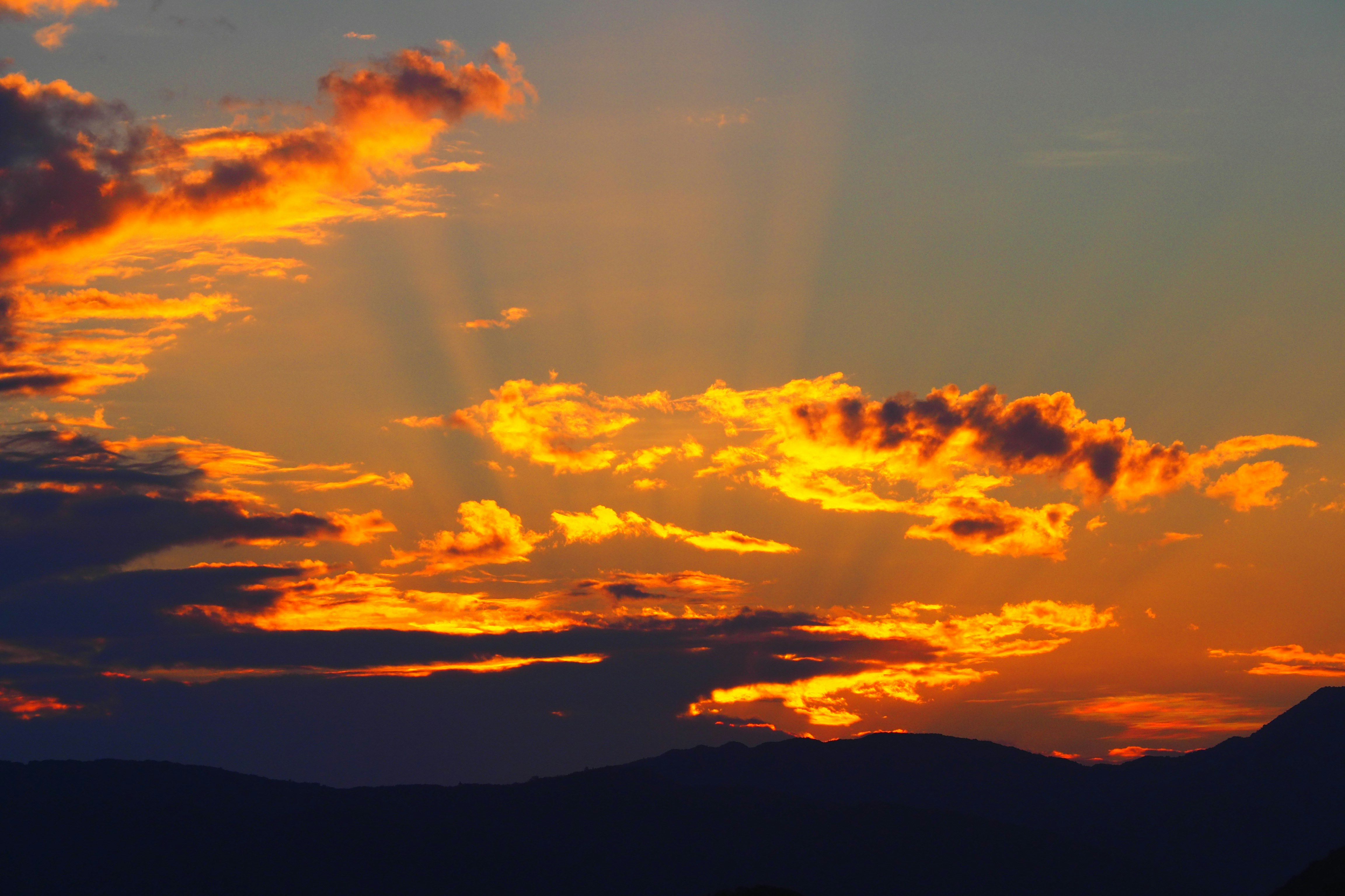 夕焼けの雲が山並みを照らす空