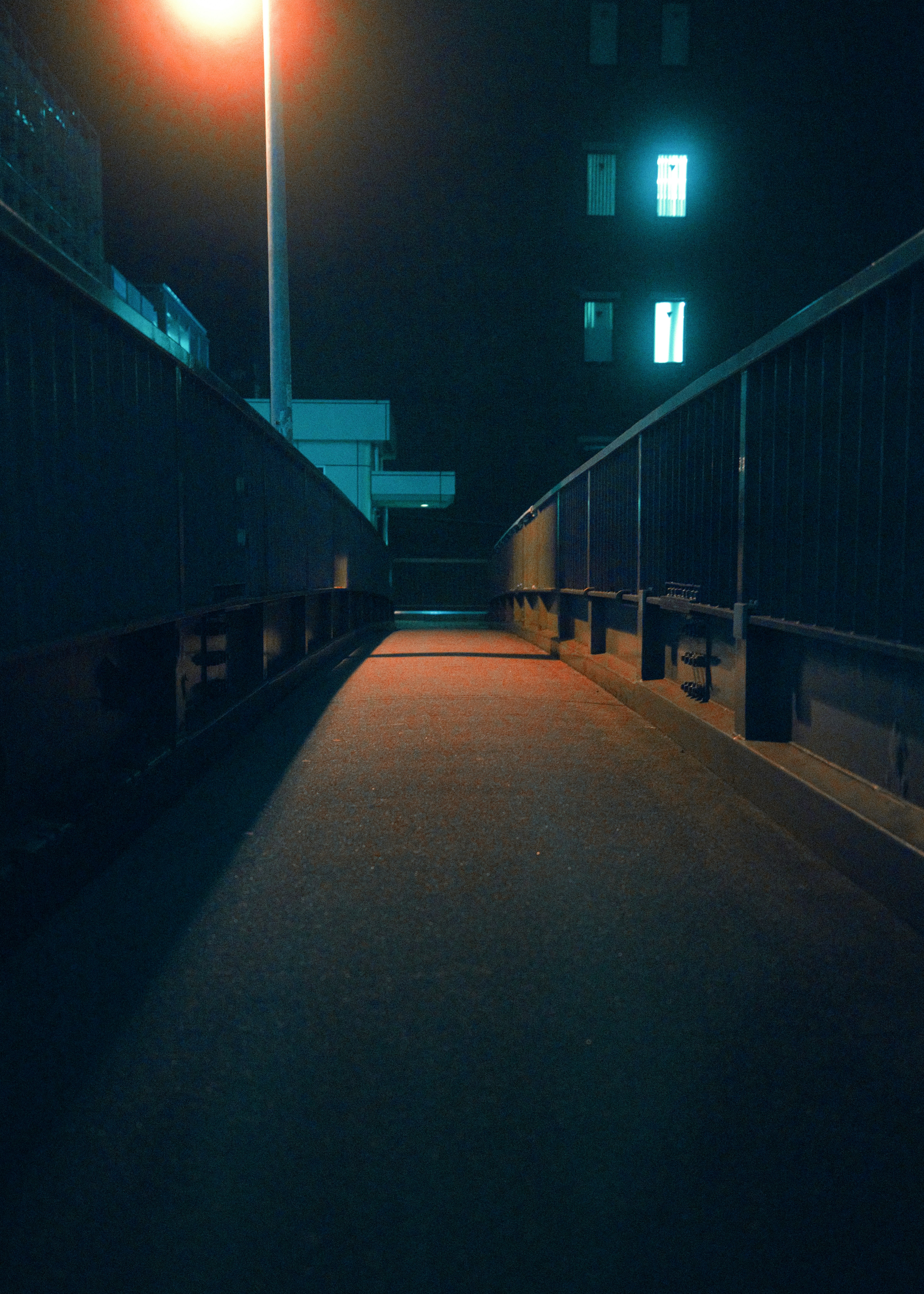 夜の路地に続く街灯と壁の並ぶ通路