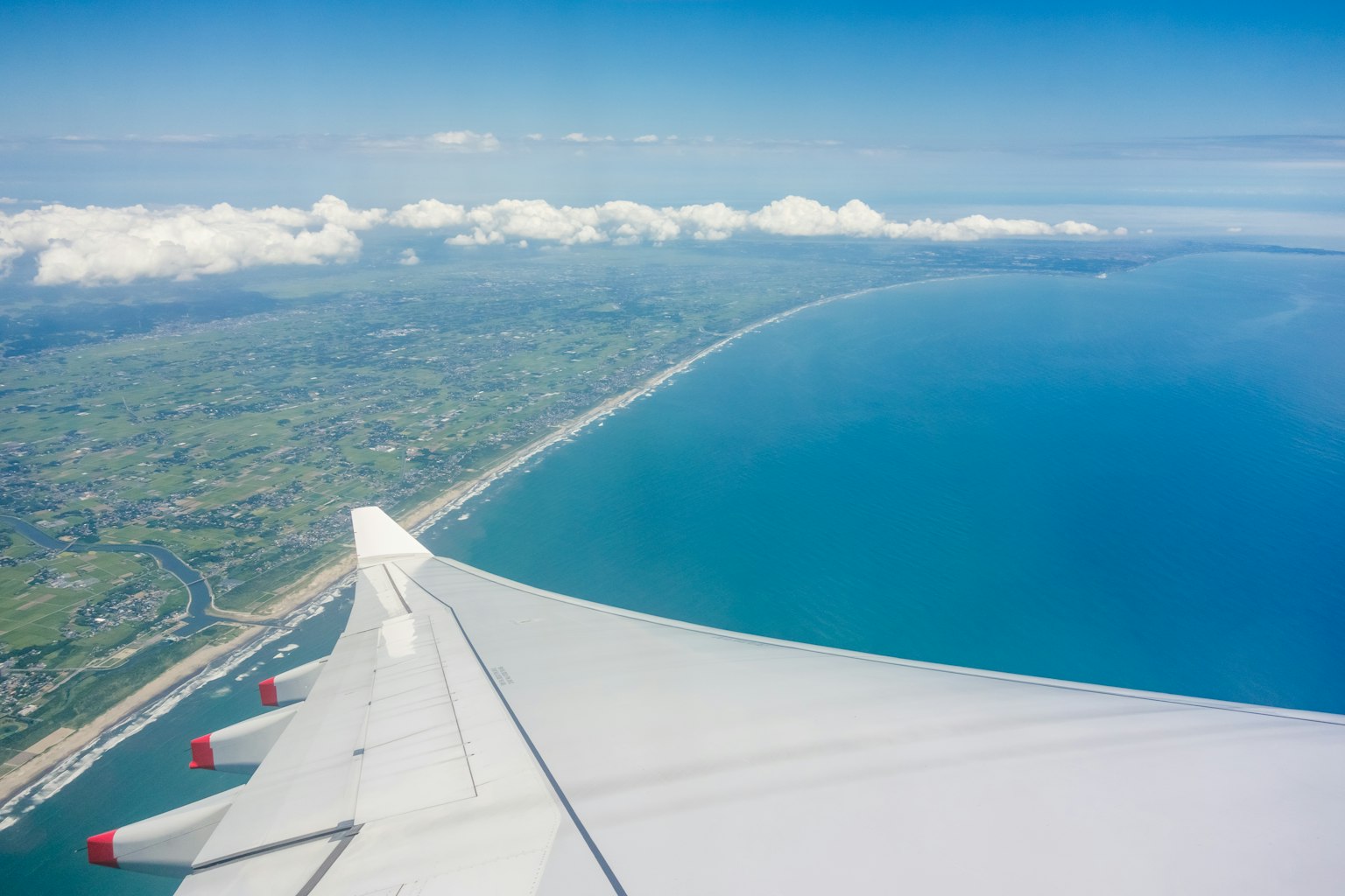 Blick auf den Ozean und Wolken vom Flugzeugflügel