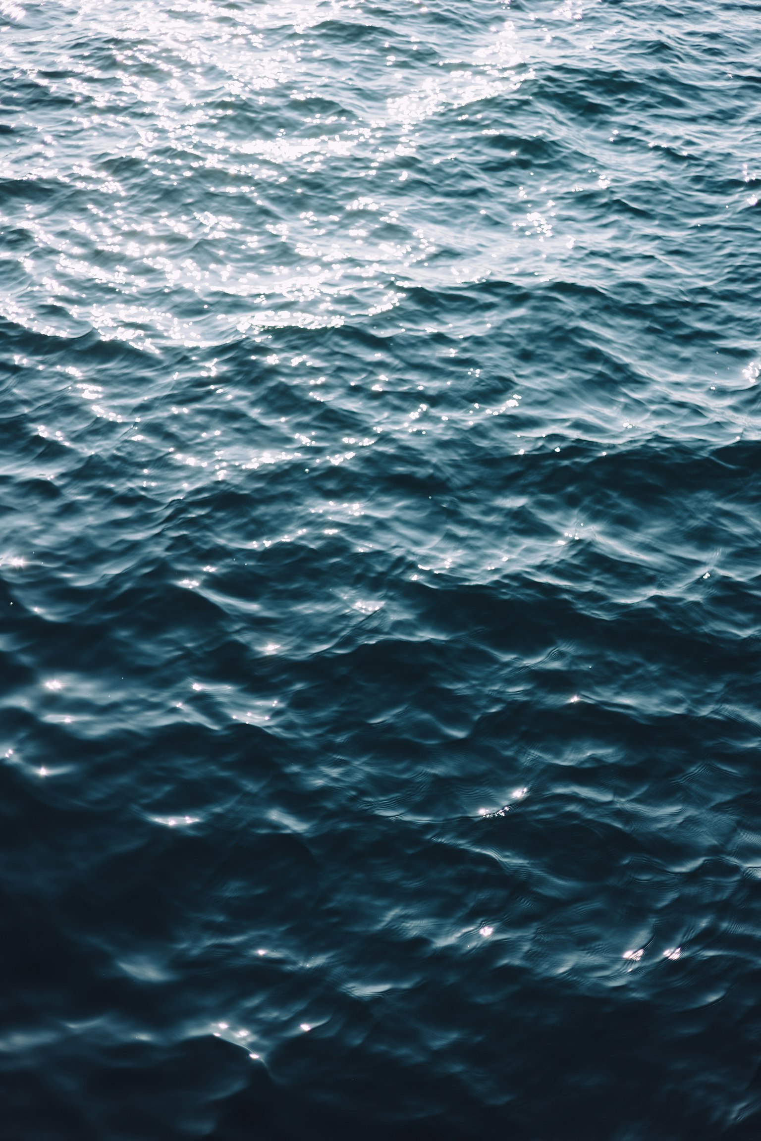 Onde calme di acqua blu dell'oceano che riflettono la luce