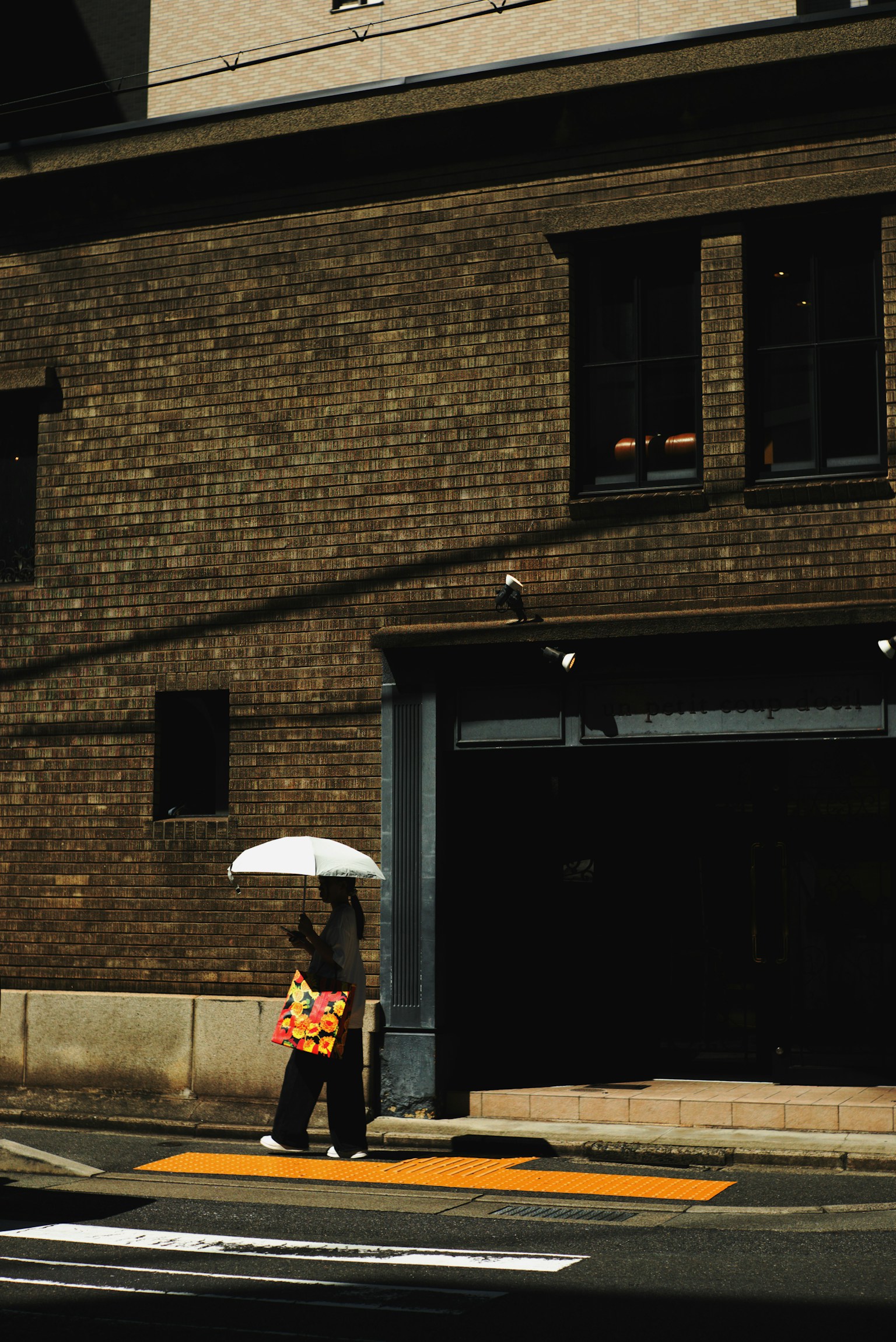傘を持って歩く人物とレンガの建物の外観