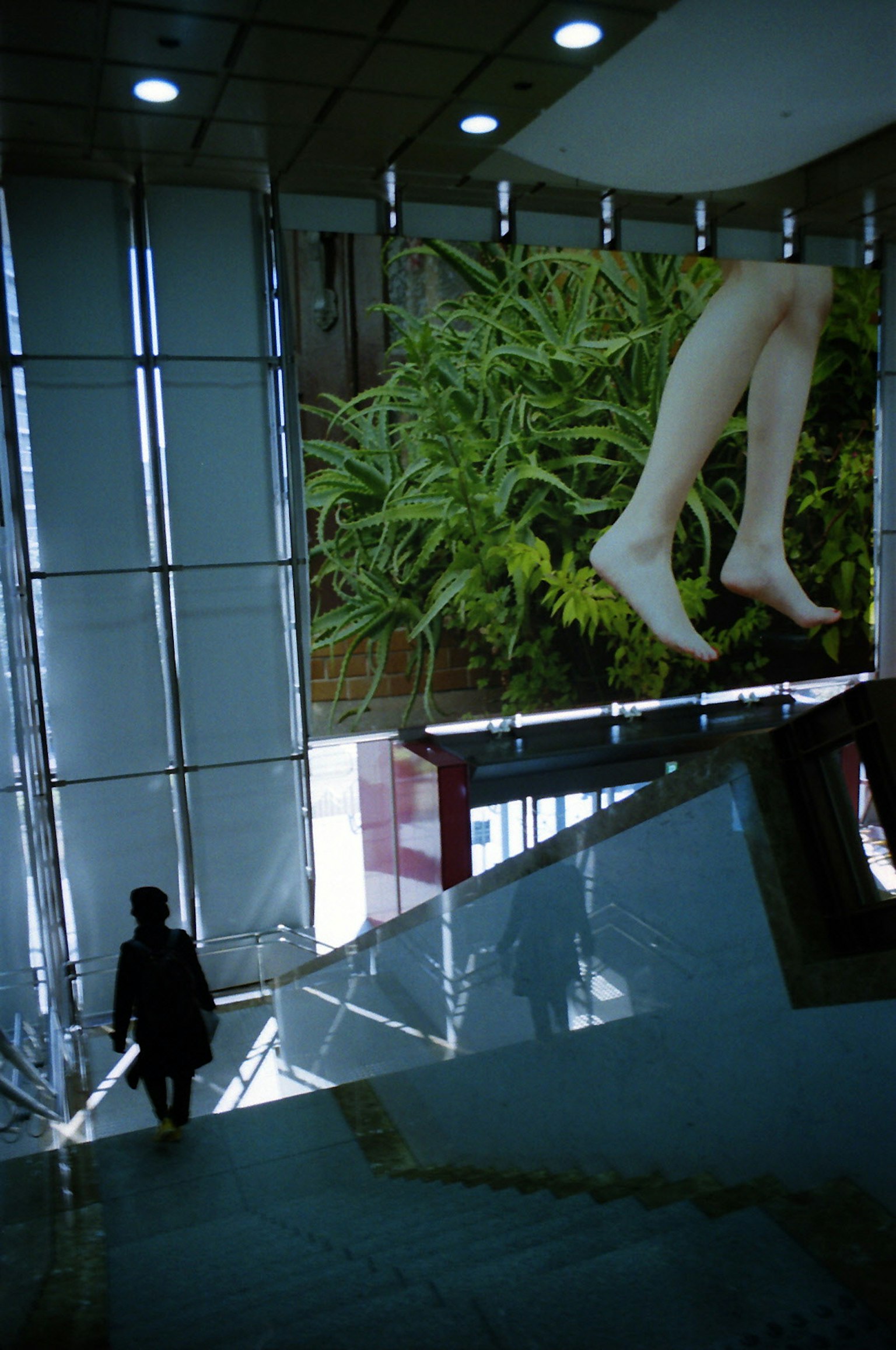 Silhouette di una persona in un edificio moderno con una grande pubblicità di gambe su sfondo verde