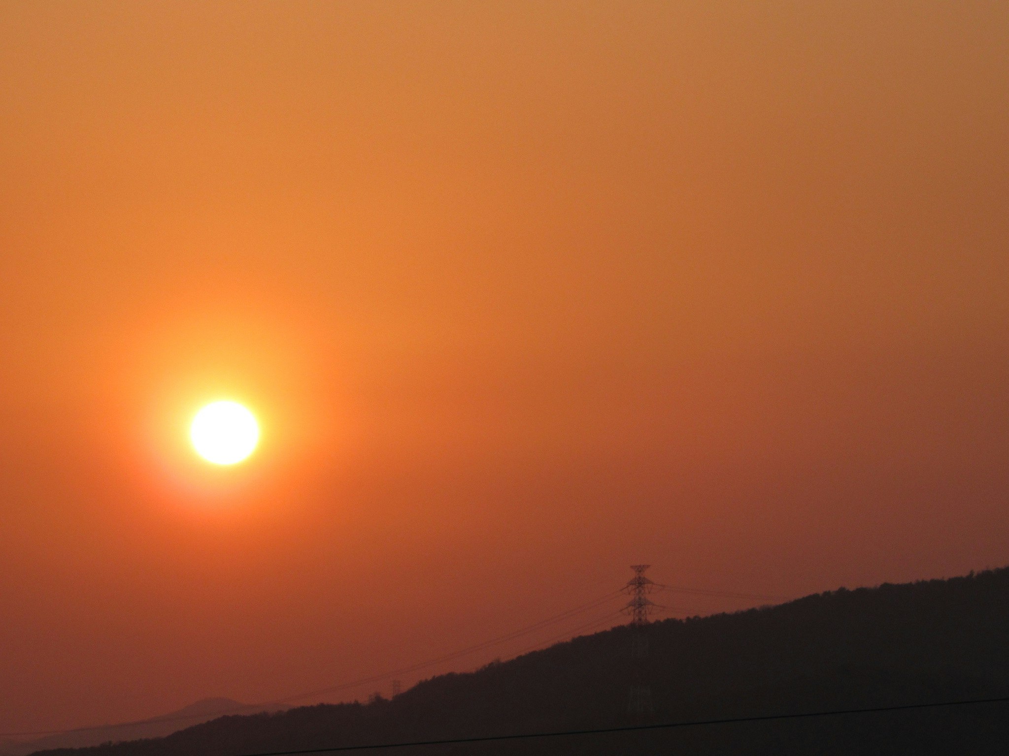 夕焼けの空と山の稜線に沈む太陽