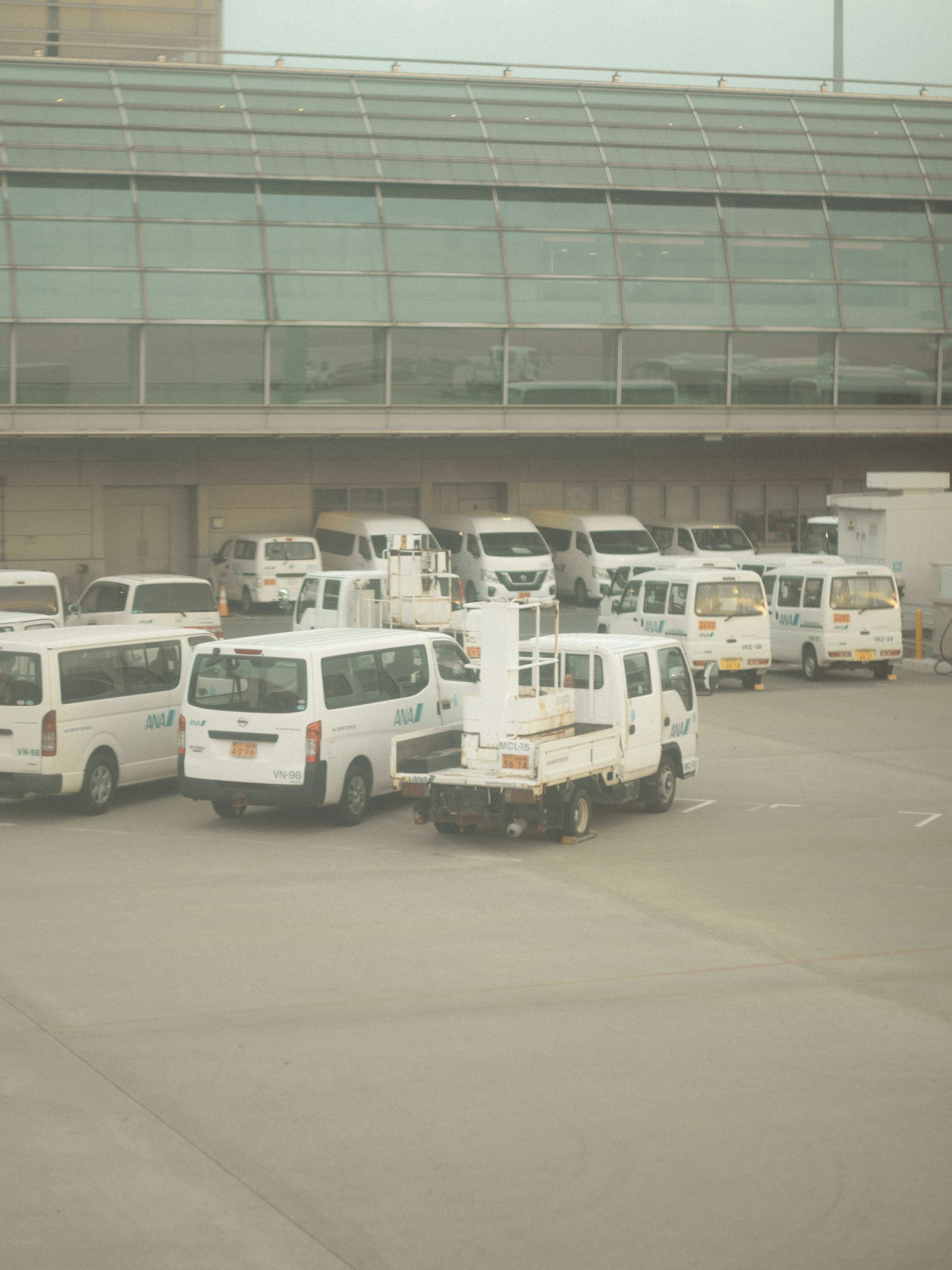 Vans et minibus blancs alignés dans un parking d'aéroport