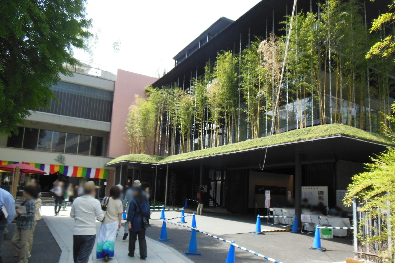 Edificio moderno con vegetación de bambú y personas caminando