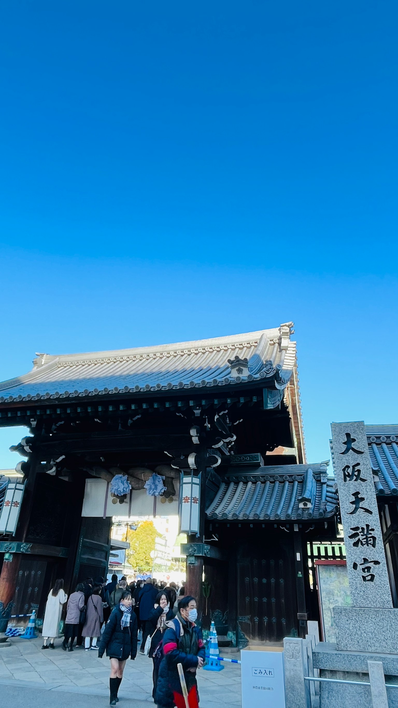 Traditional Japanese gate under a clear blue sky with people walking