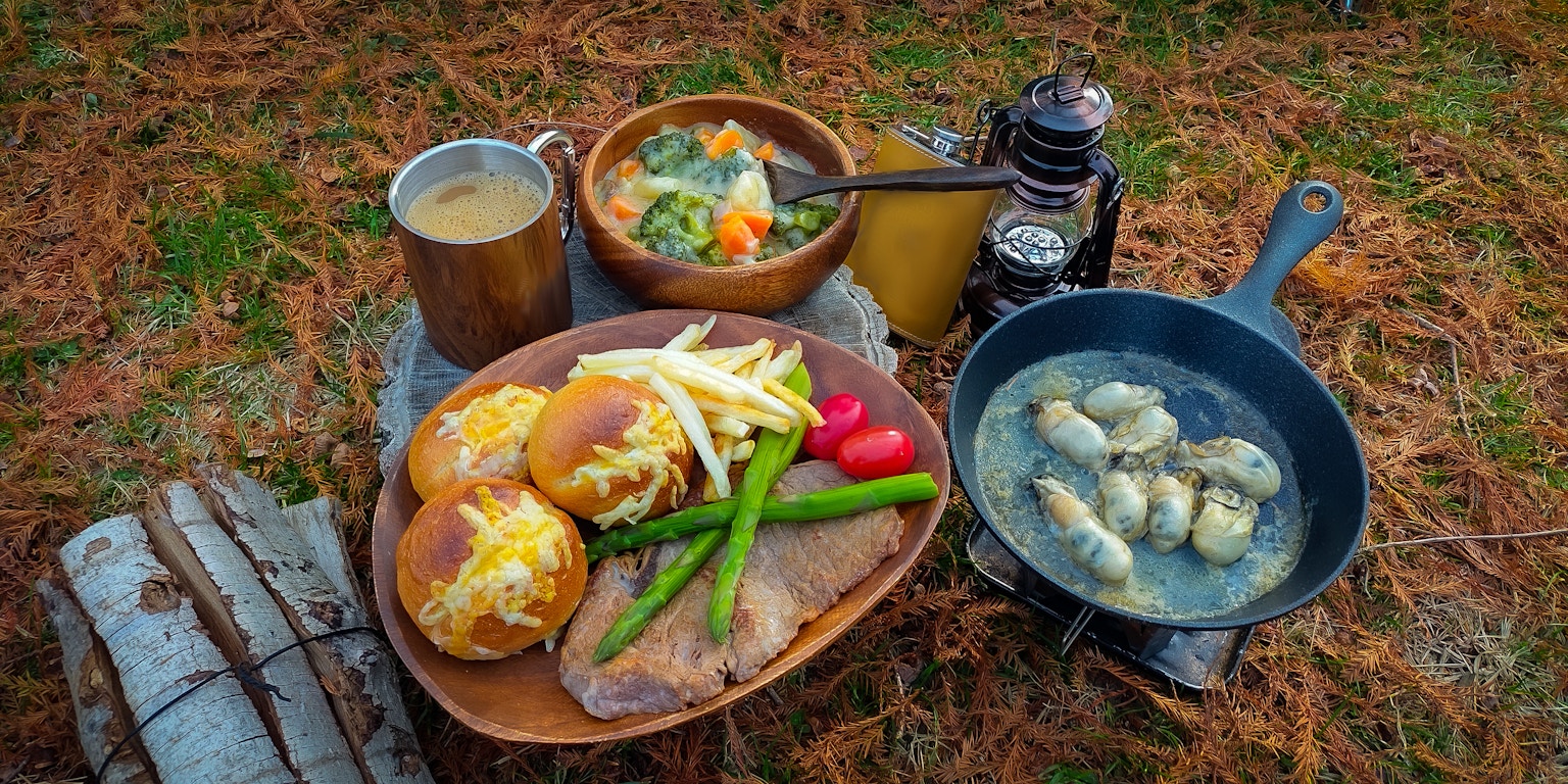 露营餐点，包含蔬菜和肉的盘子，煎锅里的饺子，户外桌子设置