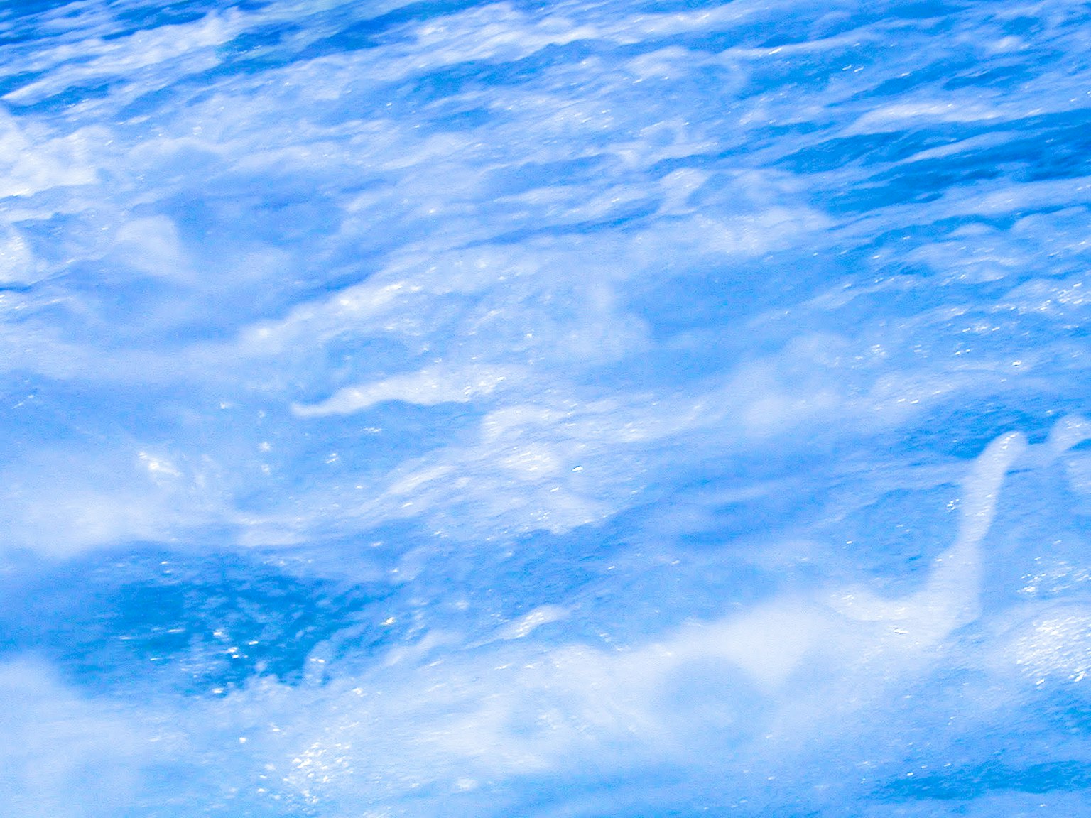 Surface of blue water with ripples and foam