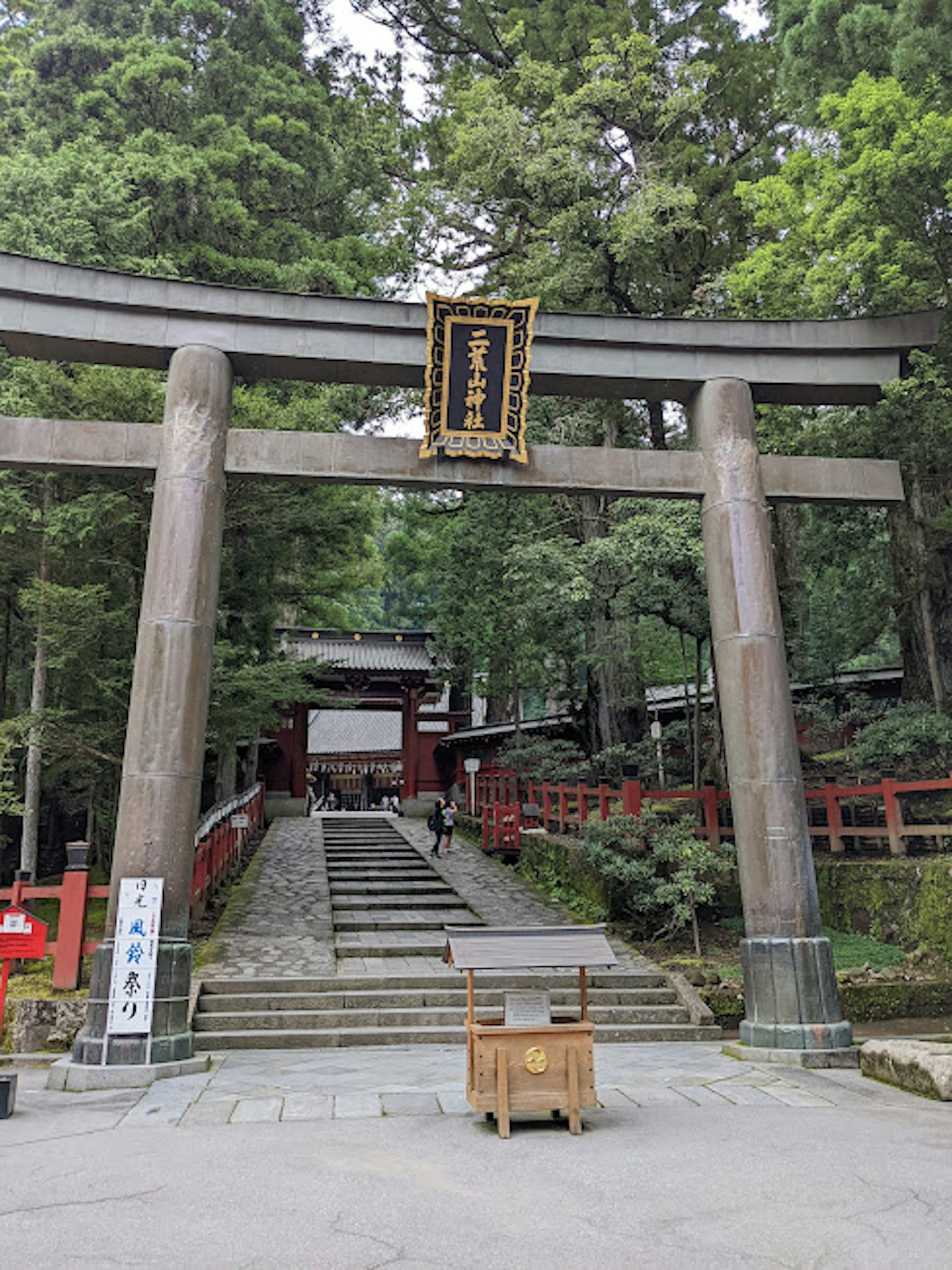 通往神社的鸟居，周围环绕着郁郁葱葱的绿树