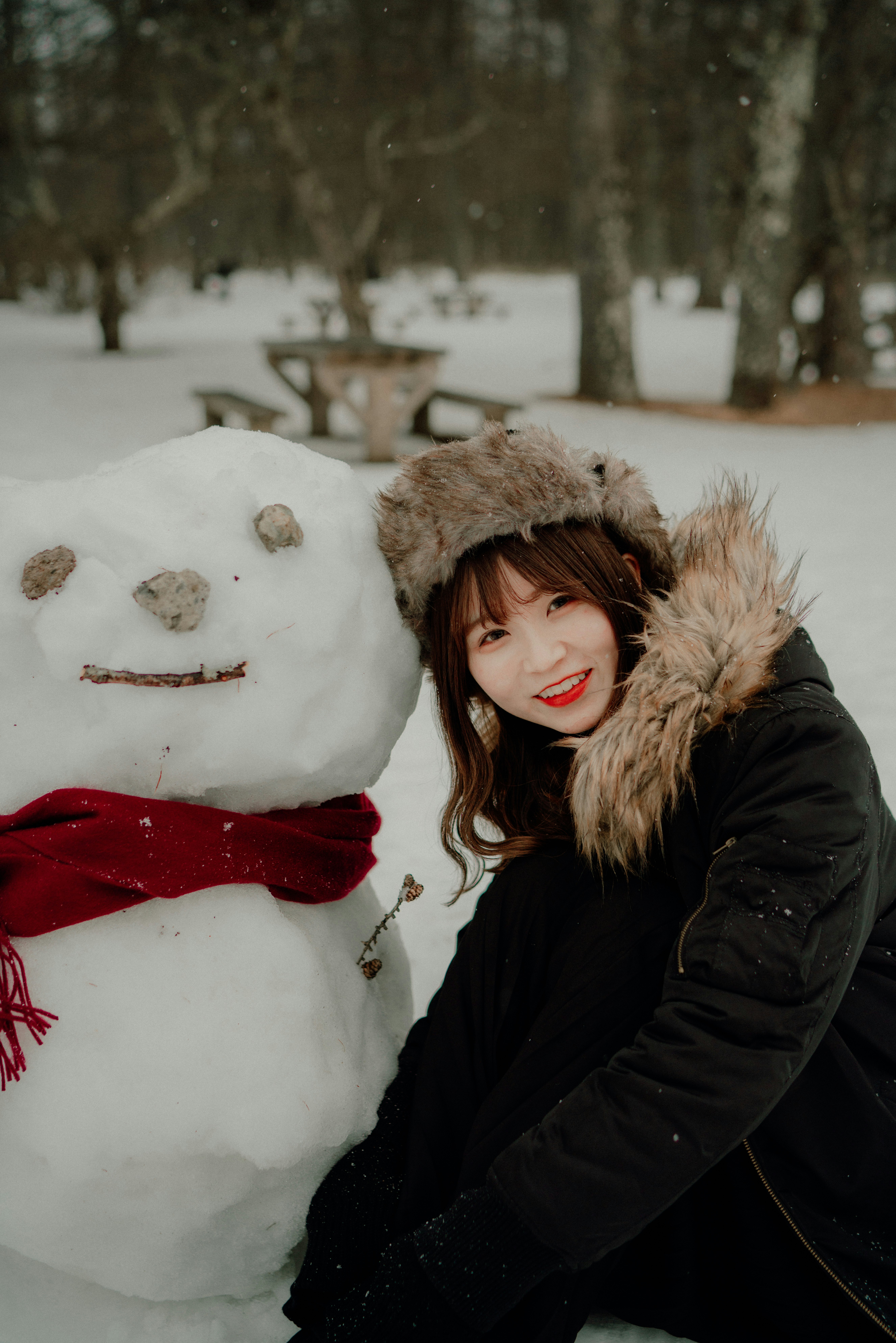 người phụ nữ đội mũ mùa đông bên cạnh người tuyết