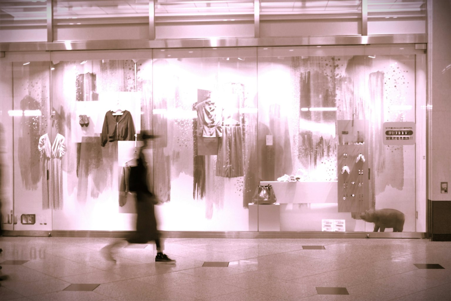 Une personne marchant devant une vitrine de mode avec divers vêtements