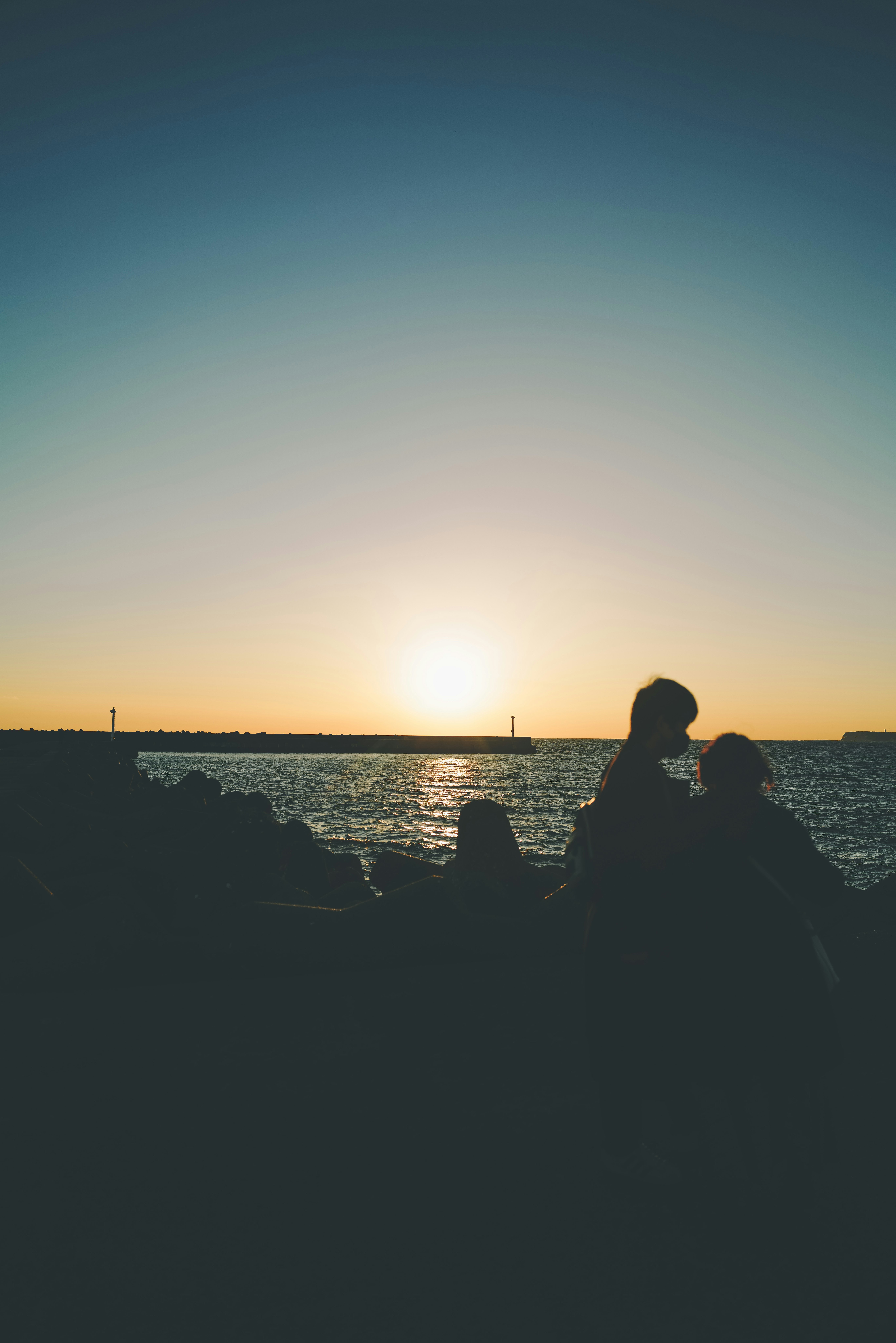 夕日に照らされる海辺でシルエットの人々