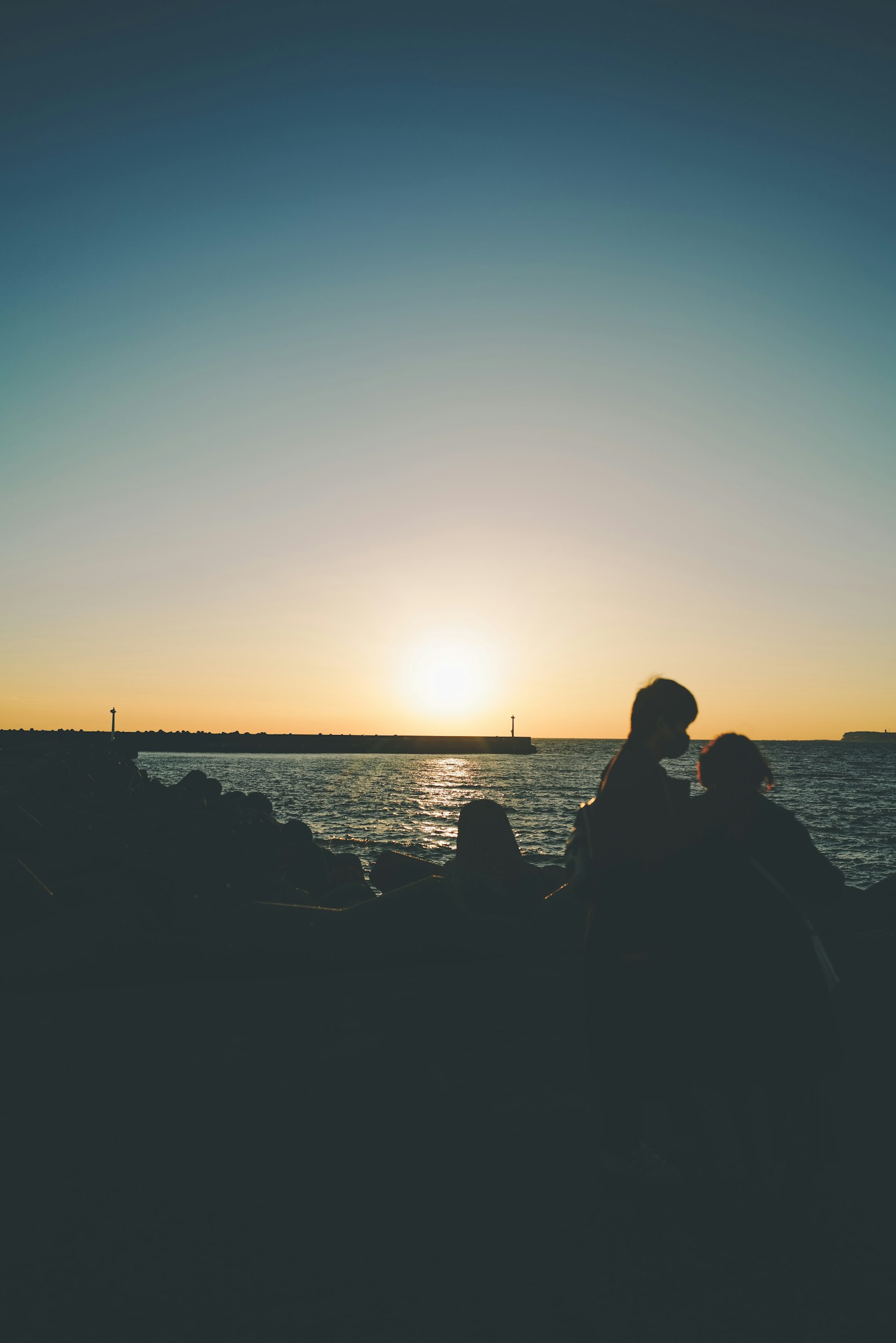 Silhouette de personnes au bord de la mer avec le coucher de soleil en arrière-plan