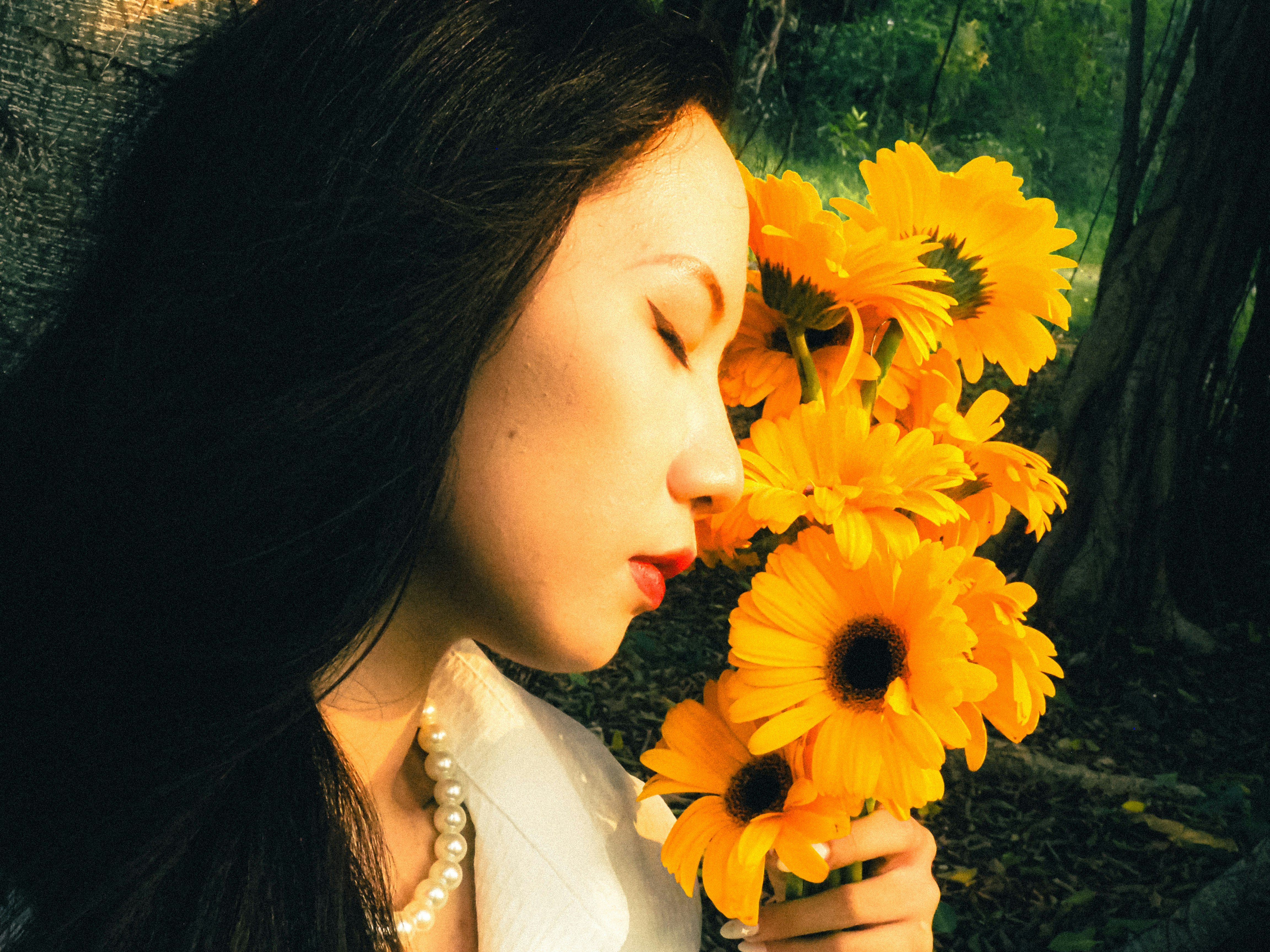 ひまわりの花束を抱く横顔の女性