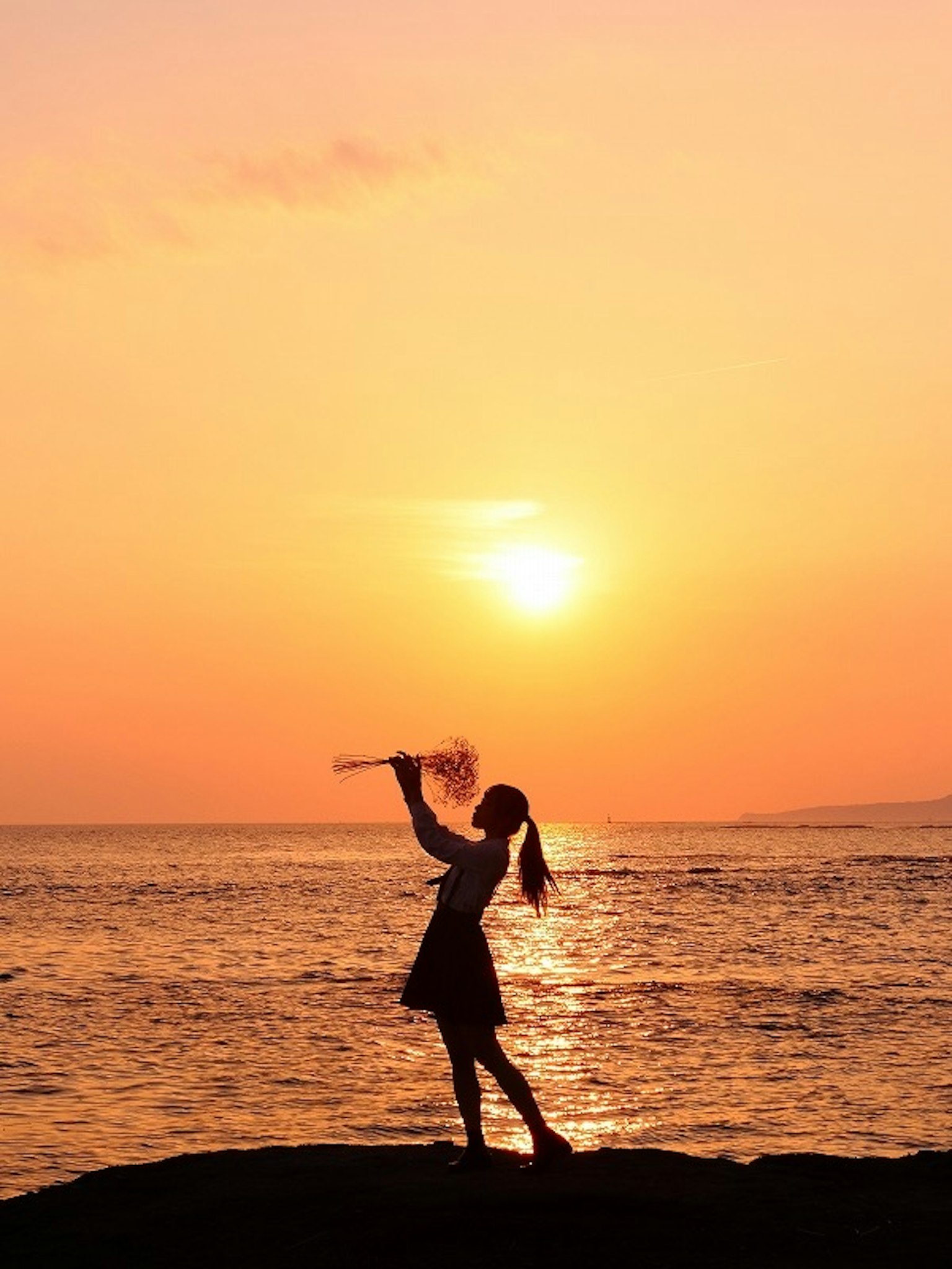 海邊夕陽下跳舞的女孩剪影