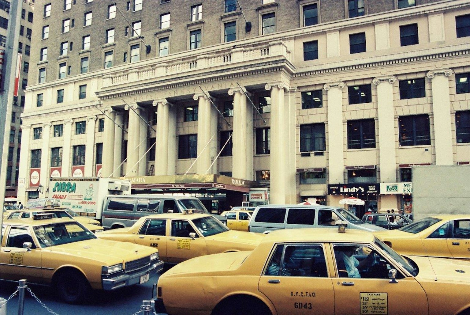 Escena de calle en Nueva York con taxis amarillos y edificio histórico