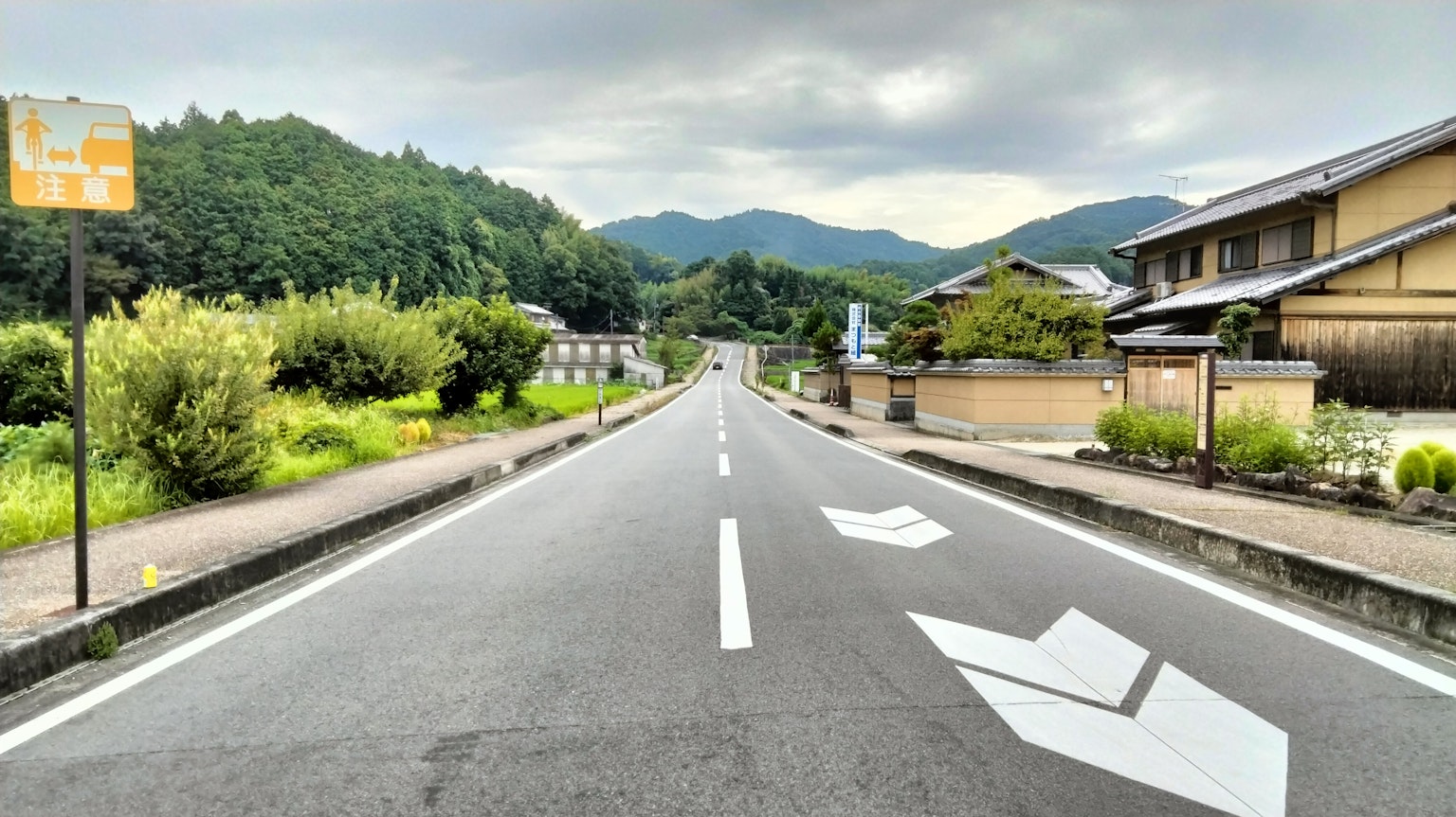 ทิวทัศน์ชนบทที่เงียบสงบมีถนนที่มีเครื่องหมายสีขาวและภูเขา