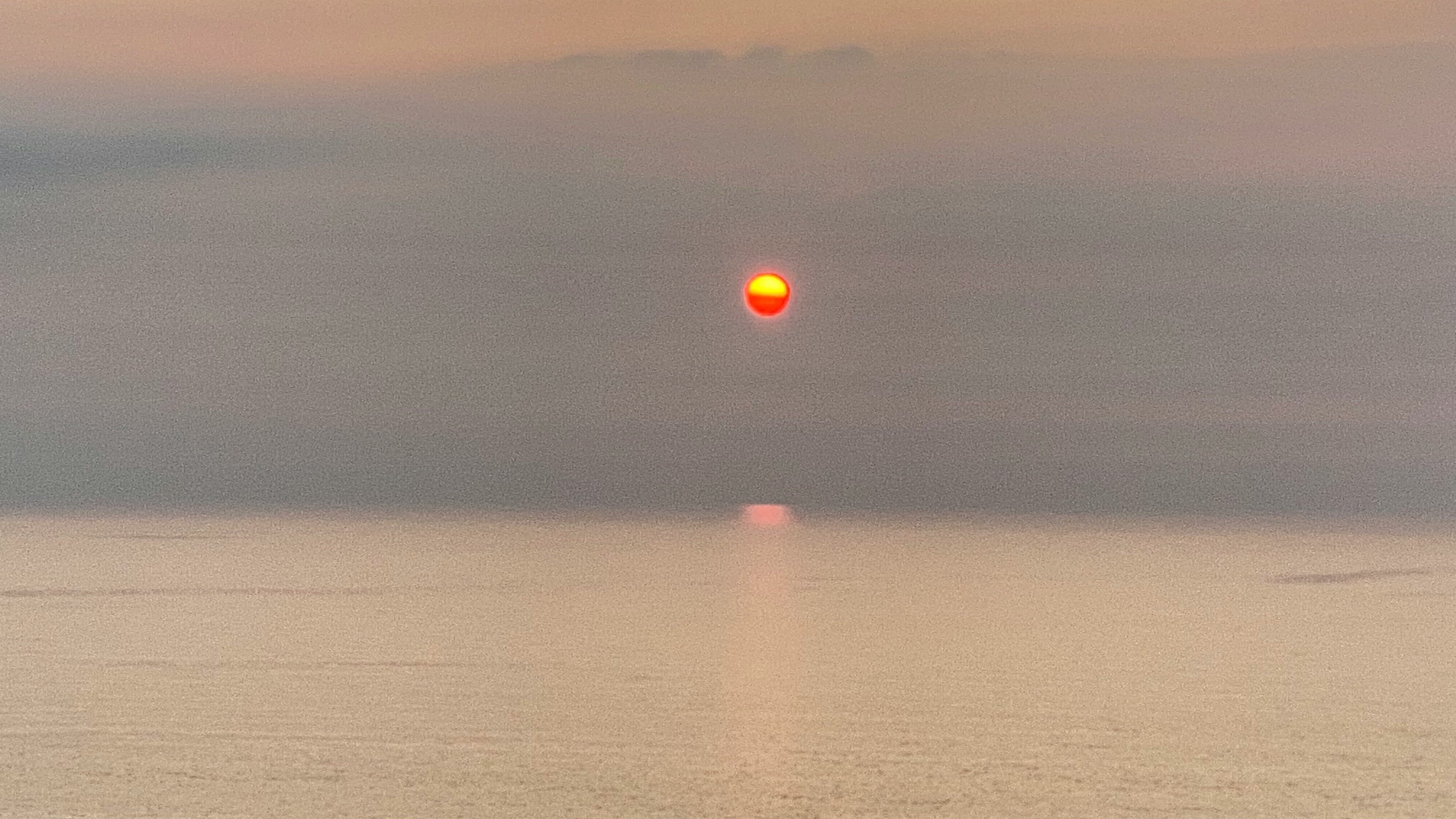 sunset sun on the horizon with reflections on the sea