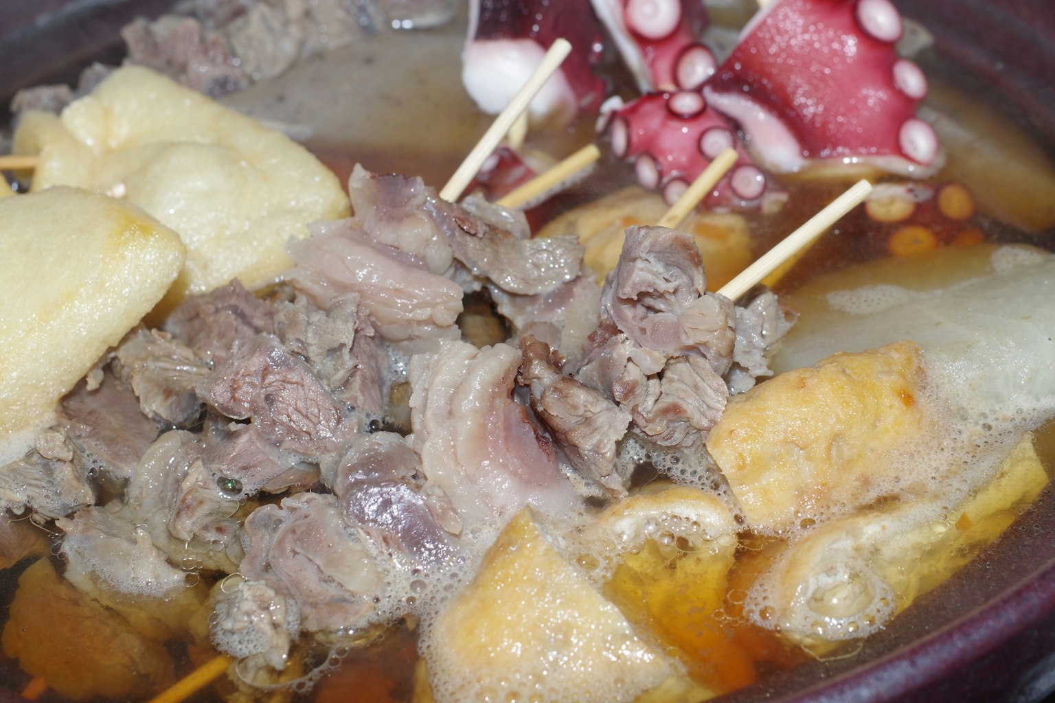 Daging dan gurita yang disajikan dalam panci mendidih