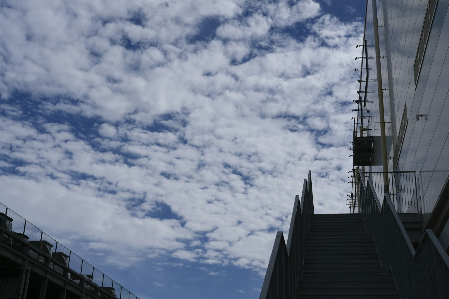 Scala che porta a un edificio sotto un cielo blu con nuvole soffici