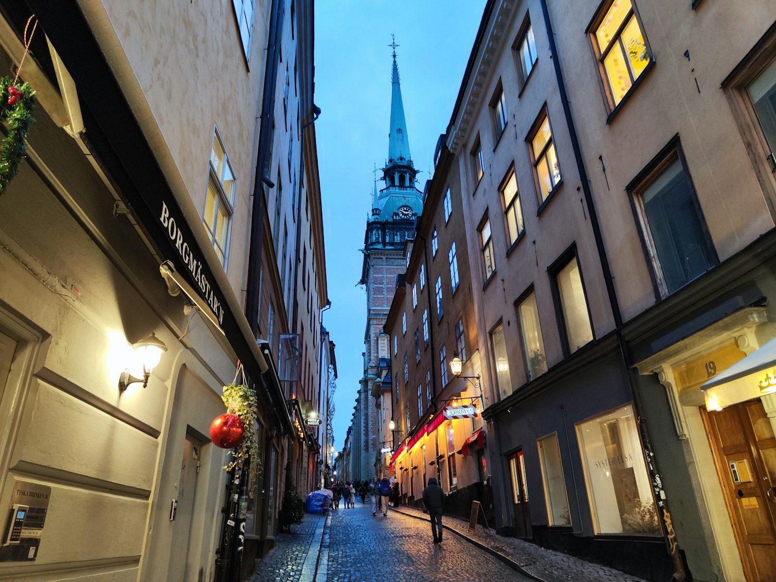 Calle estrecha con edificios históricos y campanario al anochecer