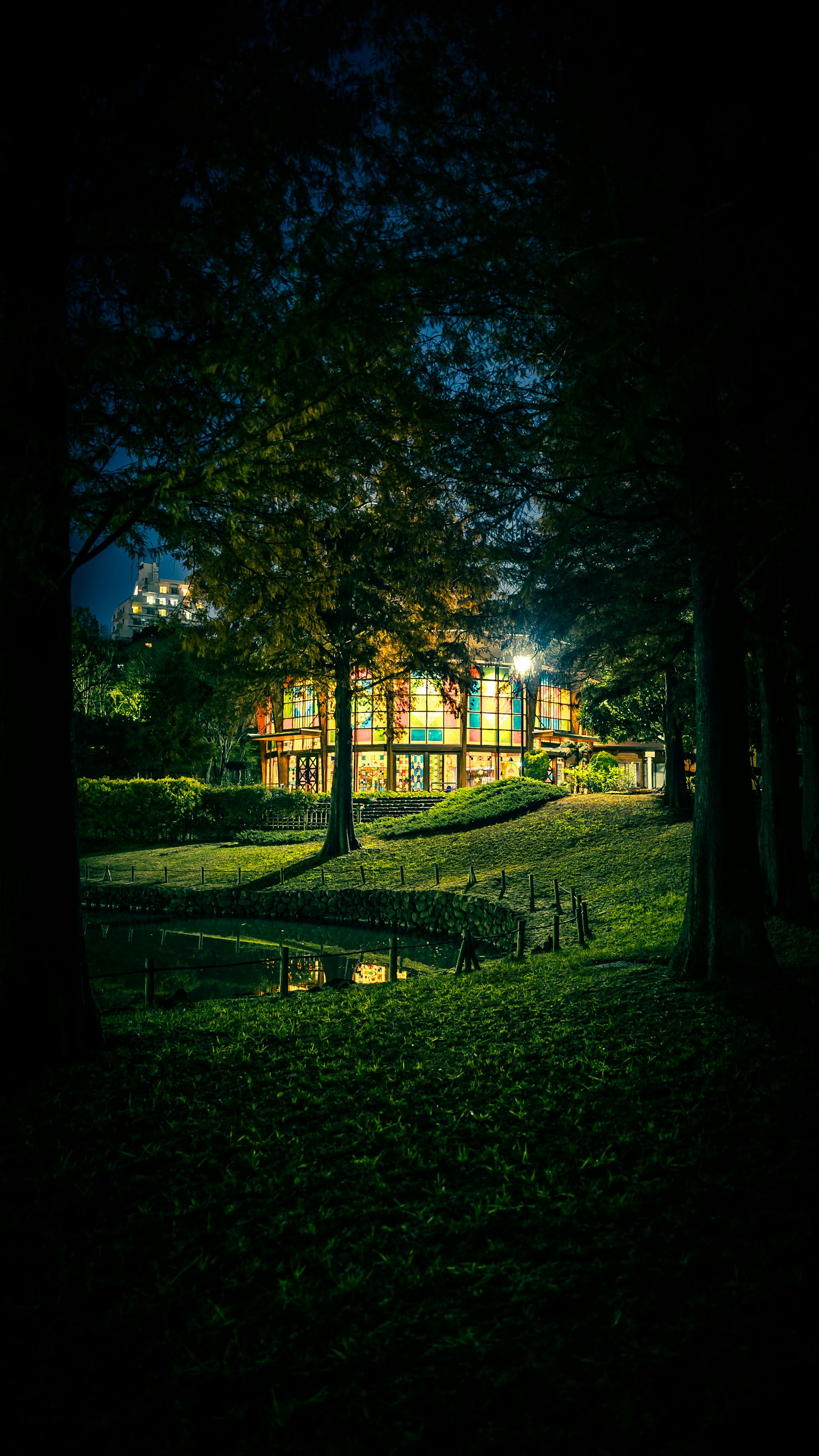 Schönes Haus bei Nacht beleuchtet mit einem ruhigen Teich und Bäumen